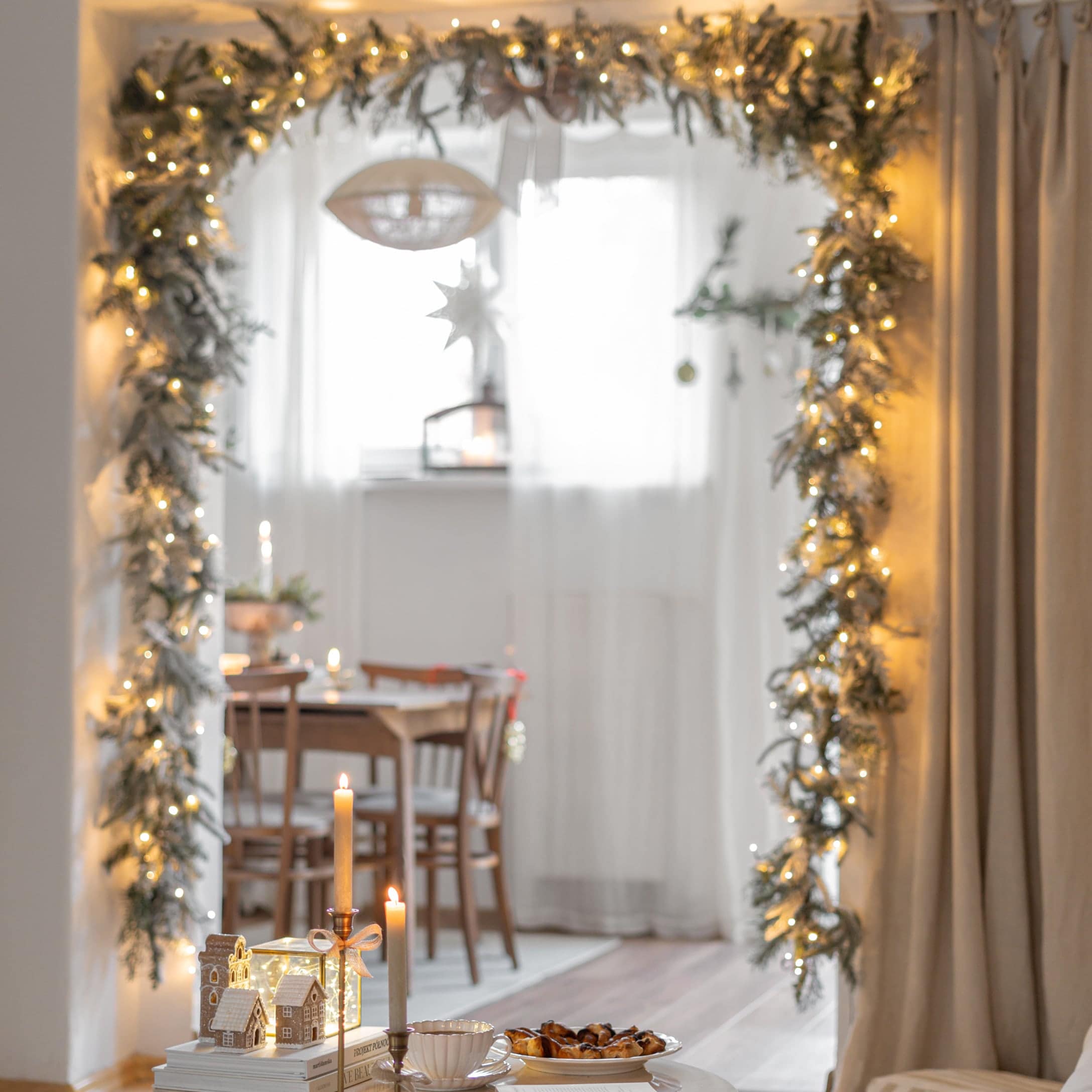 Weihnachtliche Dekoration mit Lichtergirlande und Kerzen in gemütlichem Raum mit Holztisch
