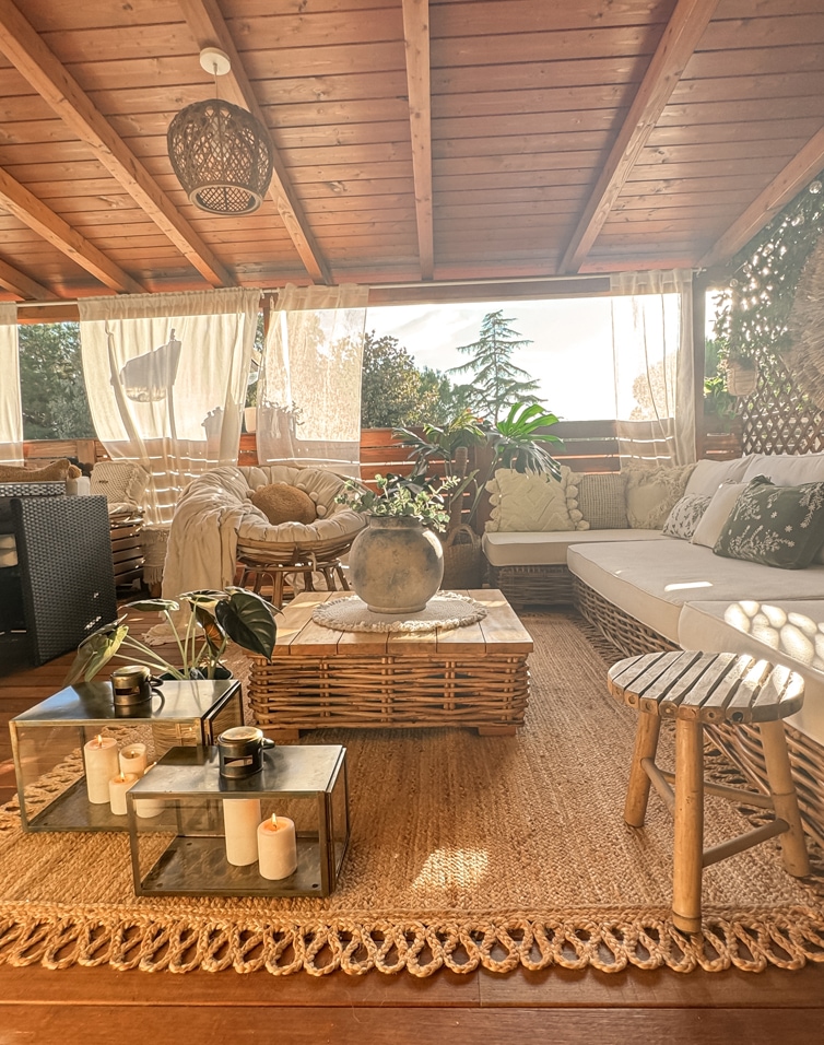 Gemütliche Terrasse mit Rattanmöbeln, Holztisch, Naturstoffen und Pflanzen als Dekoration