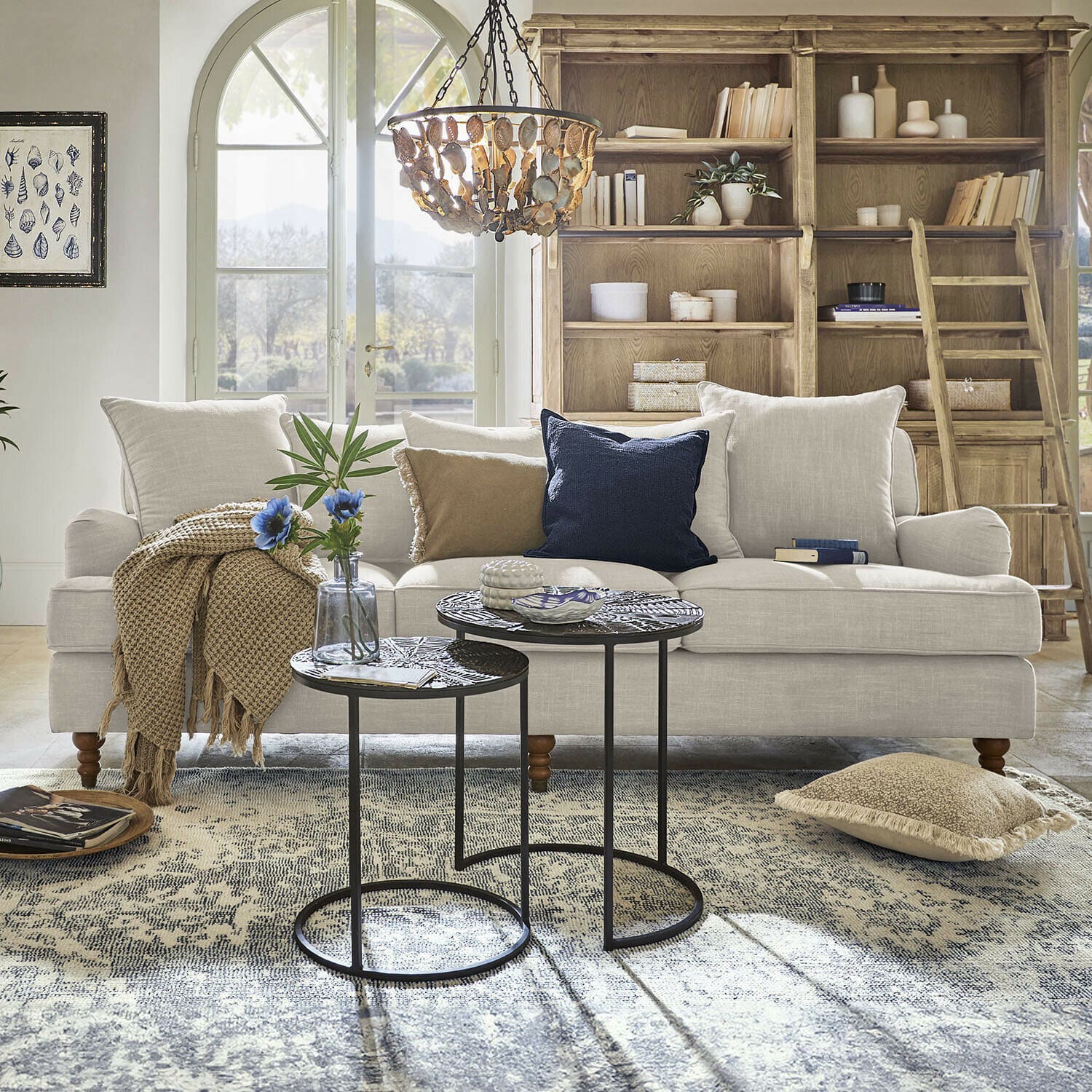 Beige bezogener Sofa mit Kissen und Holzbeinen in hellem Wohnzimmer mit Teppich