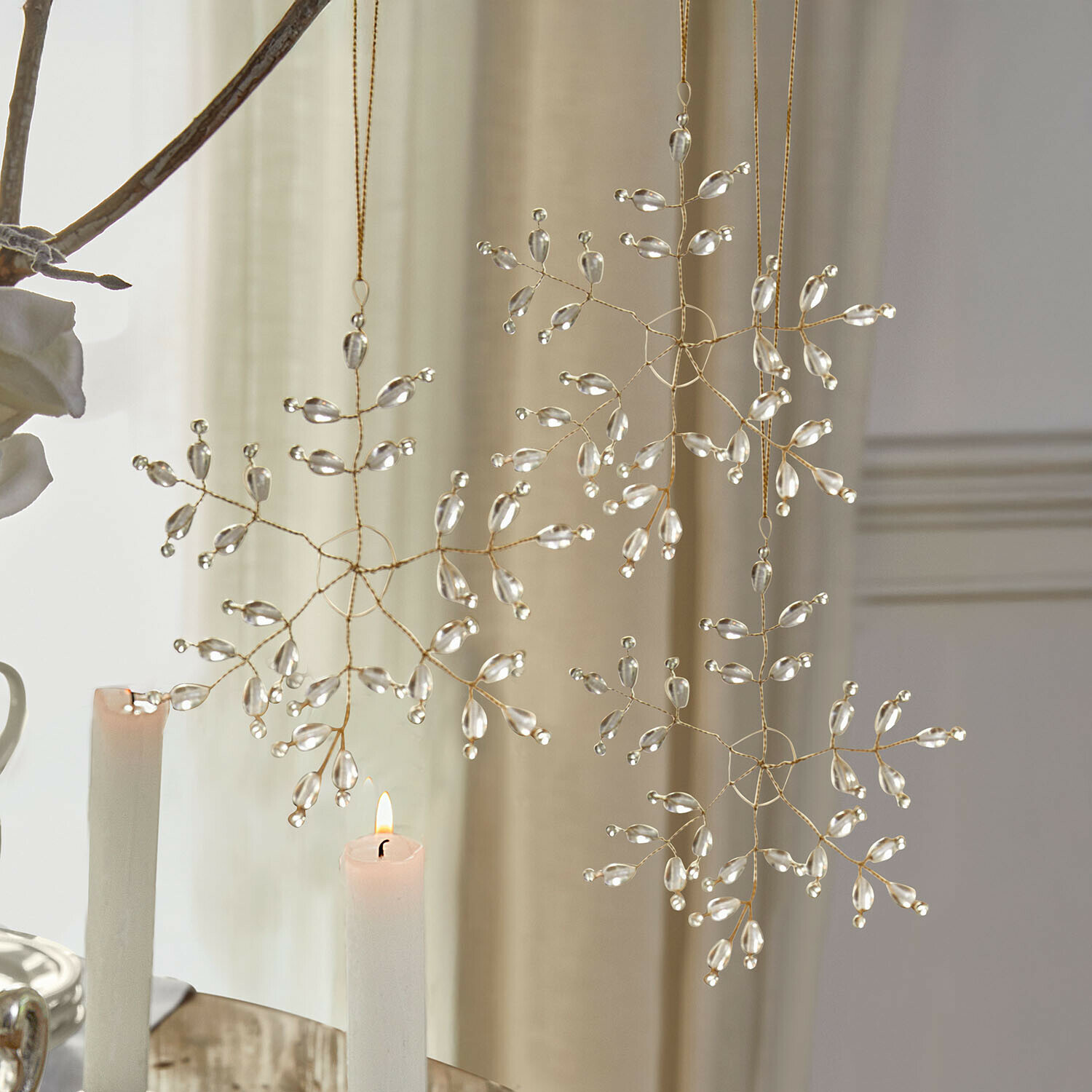 Dekorative Schneeflockenanhänger aus transparenten Perlen an goldenem Draht für Weihnachtsdeko