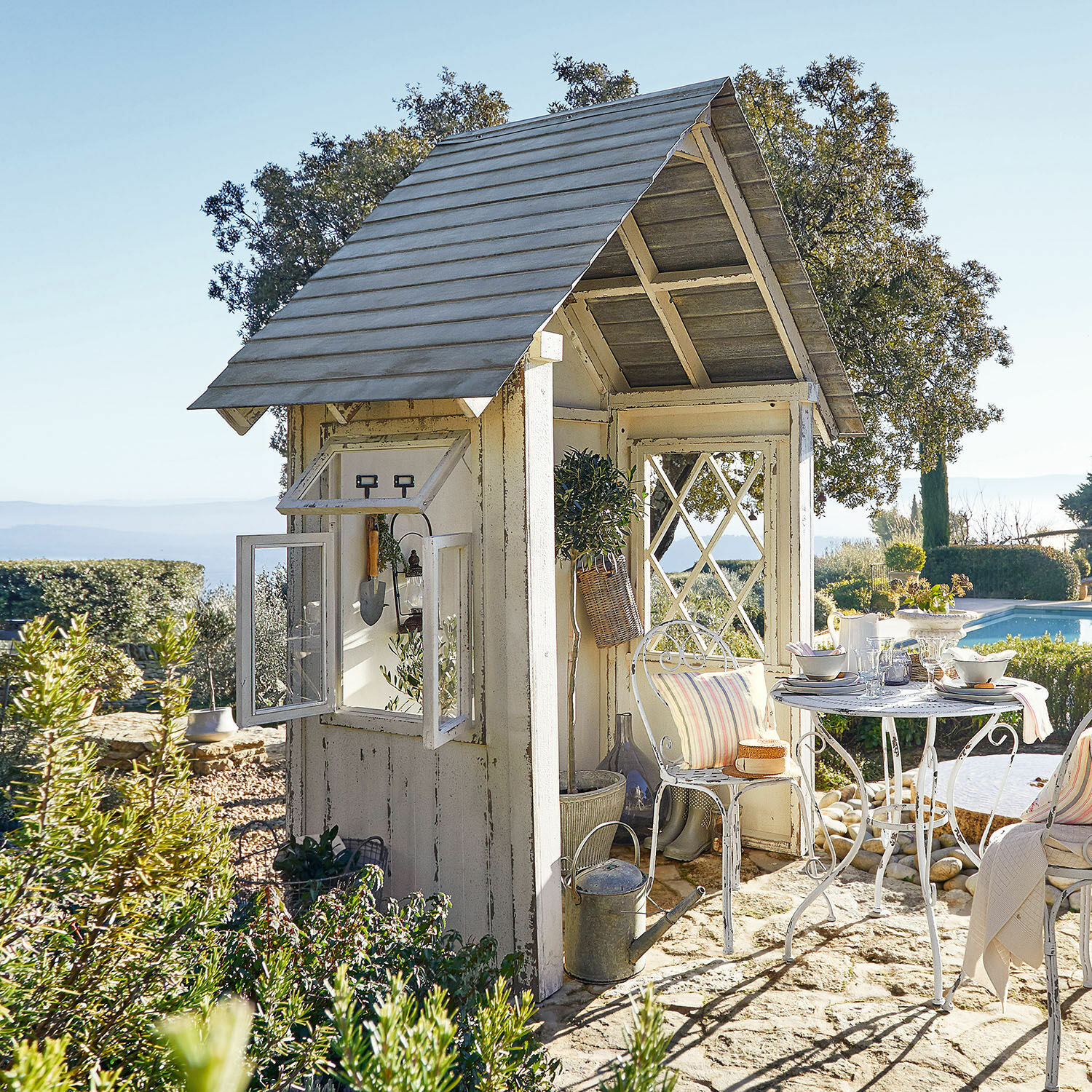 Gartenhaus Sumter Weiße Holz-Gartenlaube mit Metalltisch und Stühlen auf Steinboden neben dem Pool