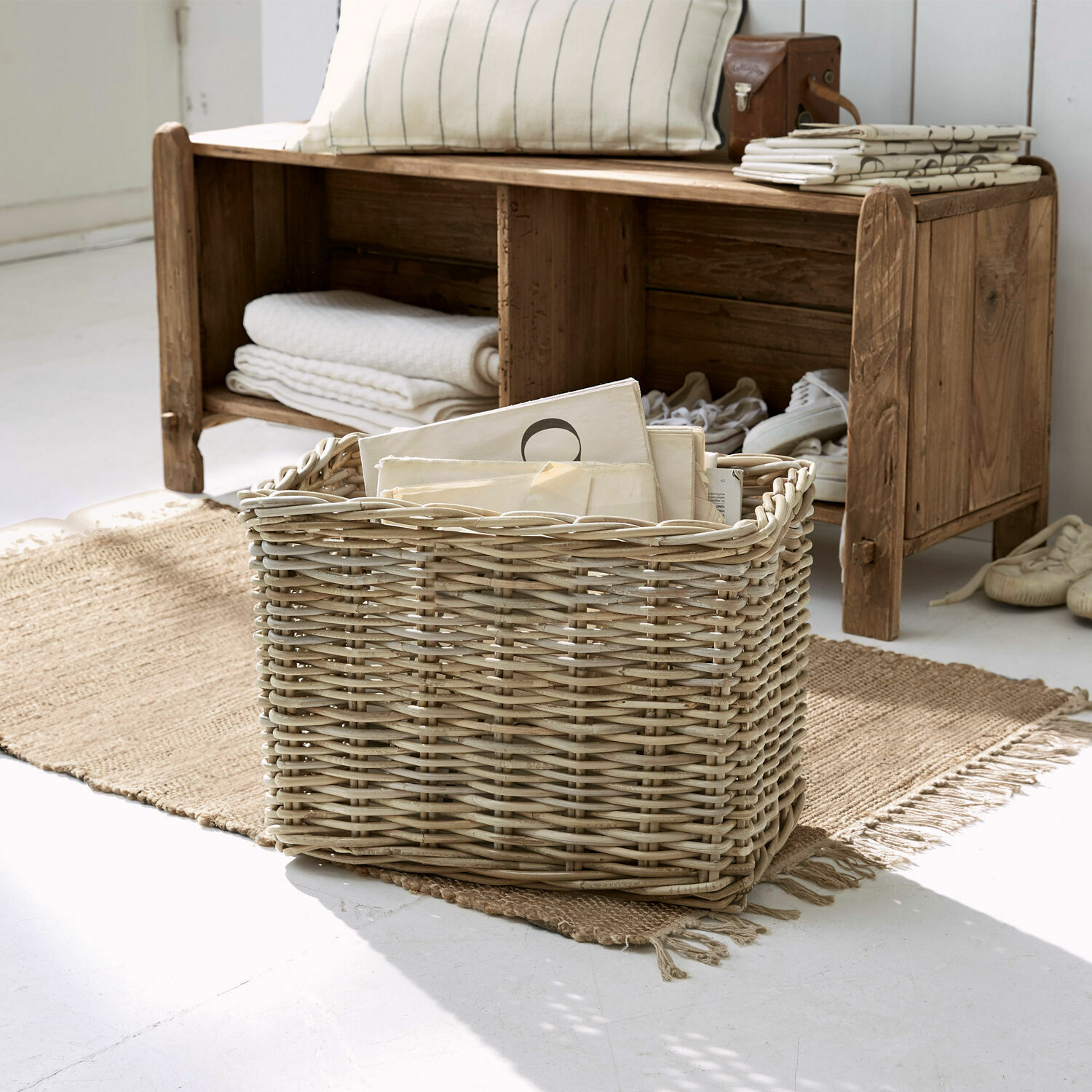 Natürlicher Korb aus Weide mit Dokumenten auf Juteteppich in hellem Raum