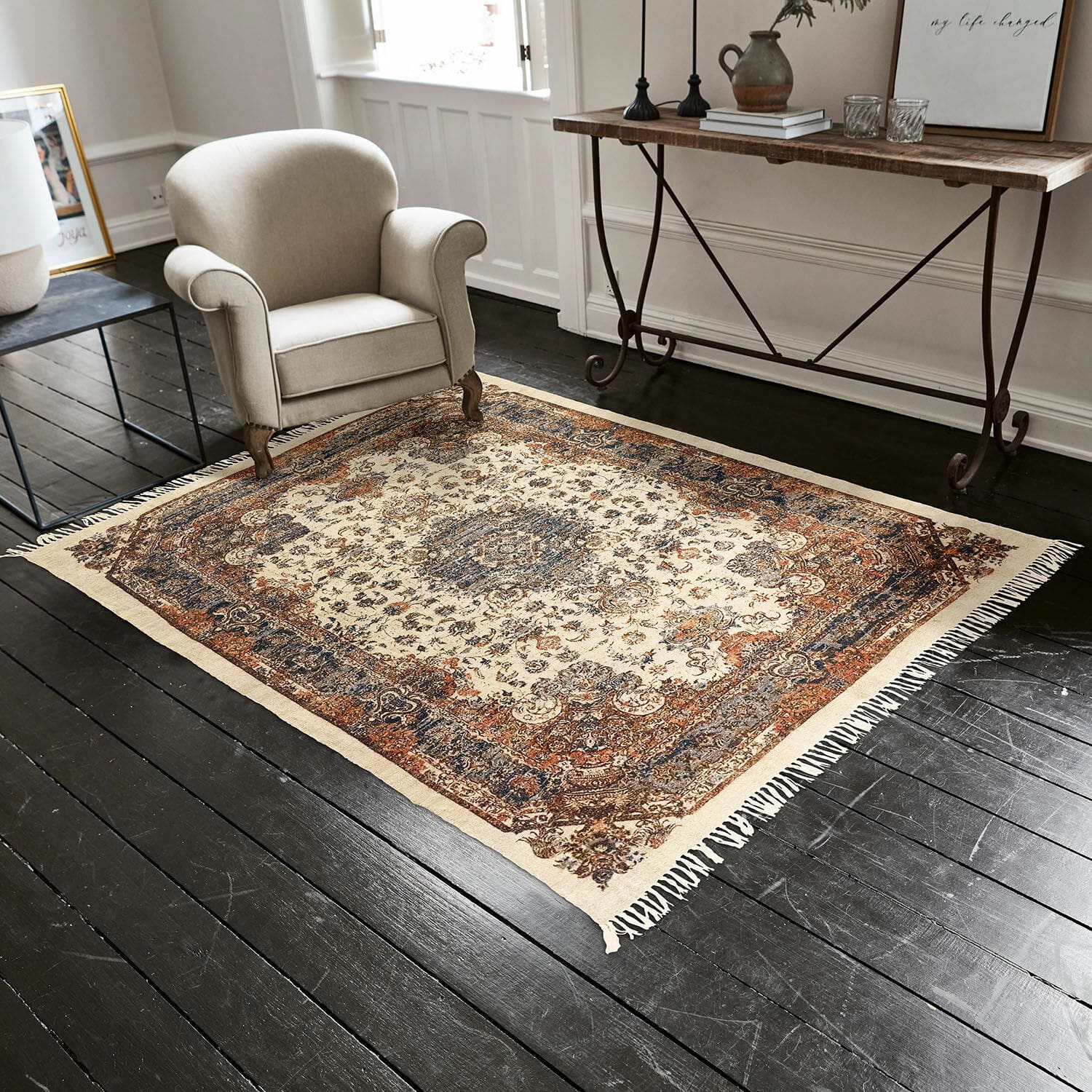 Teppich Aleixo Orientalischer Teppich in Creme, Blau und Braun auf dunklem Holzboden im Wohnzimmer
