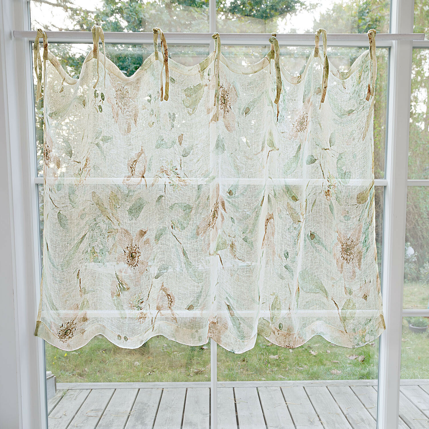 Transparenter Vorhang mit zartem Blumenmuster in Pastellfarben am Fenster