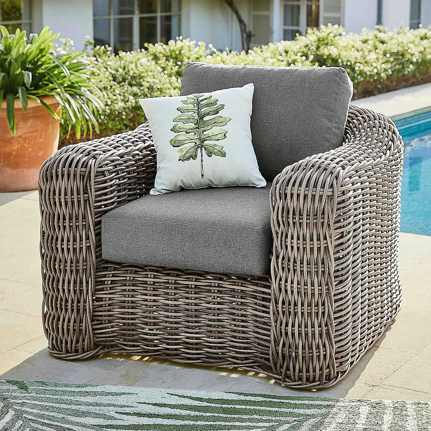 Sessel Upminster Grau geflochtener Outdoor-Sessel mit grauen Polstern und dekorativem Blattkissen am Pool