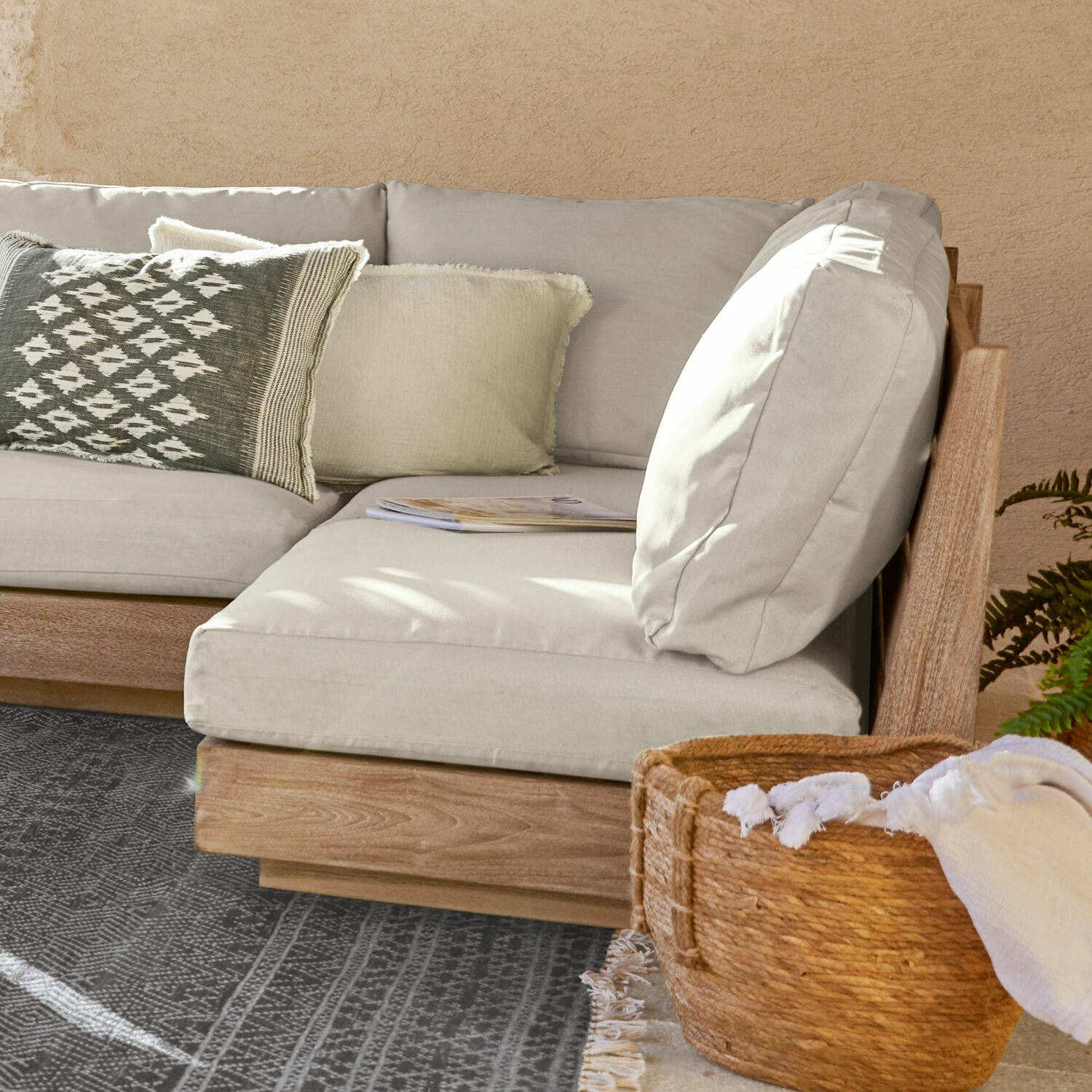 Sofaelement Courtelevant Ecksofa mit hellgrauem Stoffbezug und Holzrahmen, dekoratives Kissen und Korb mit Stoffdecke