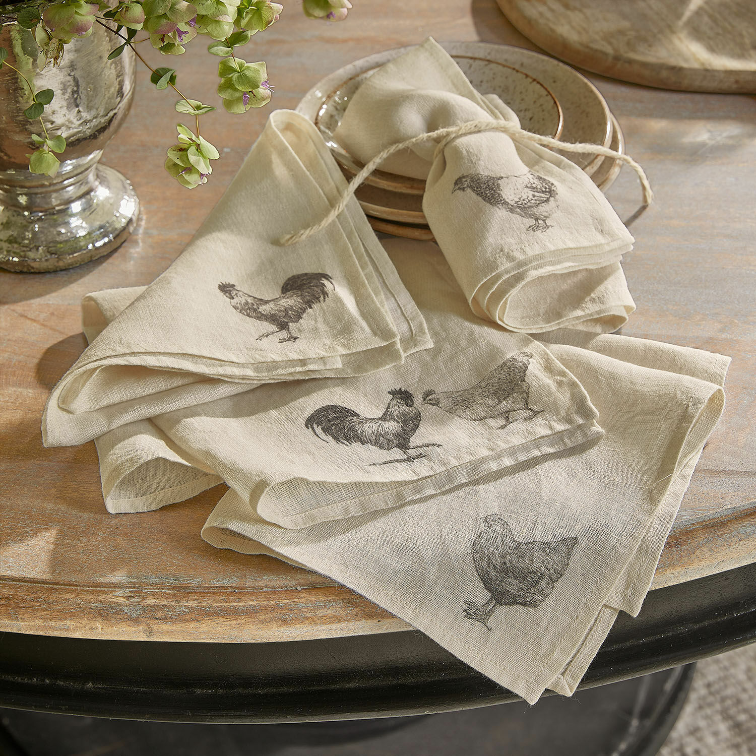 Serviette 4er Set Walorine Beige Leinen-Servietten mit Huhn- und Hahn-Motiven auf rustikalem Holztisch