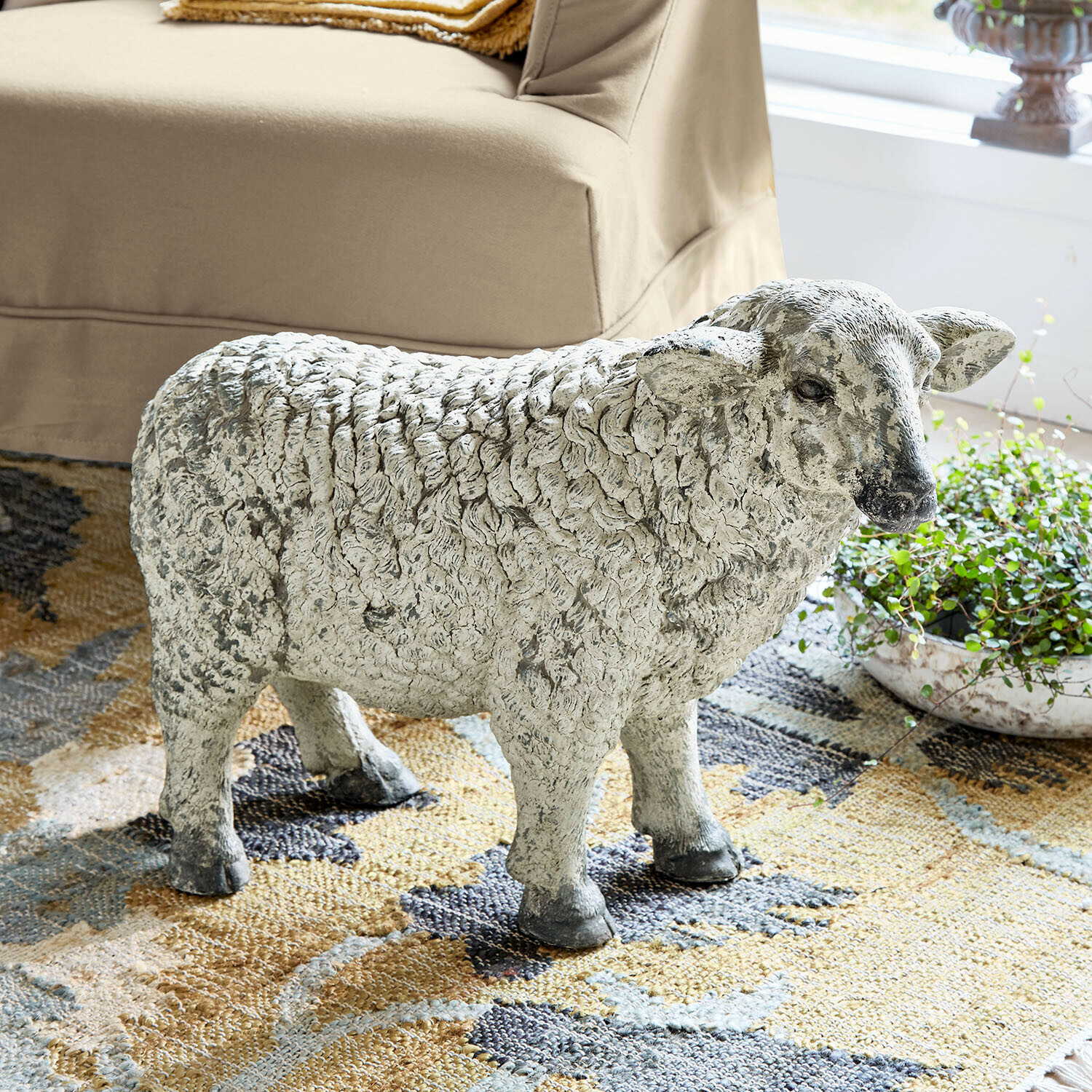 Schaffigur aus grauem Stein auf Teppich im Wohnzimmer, natürliche Wohnraumdekoration