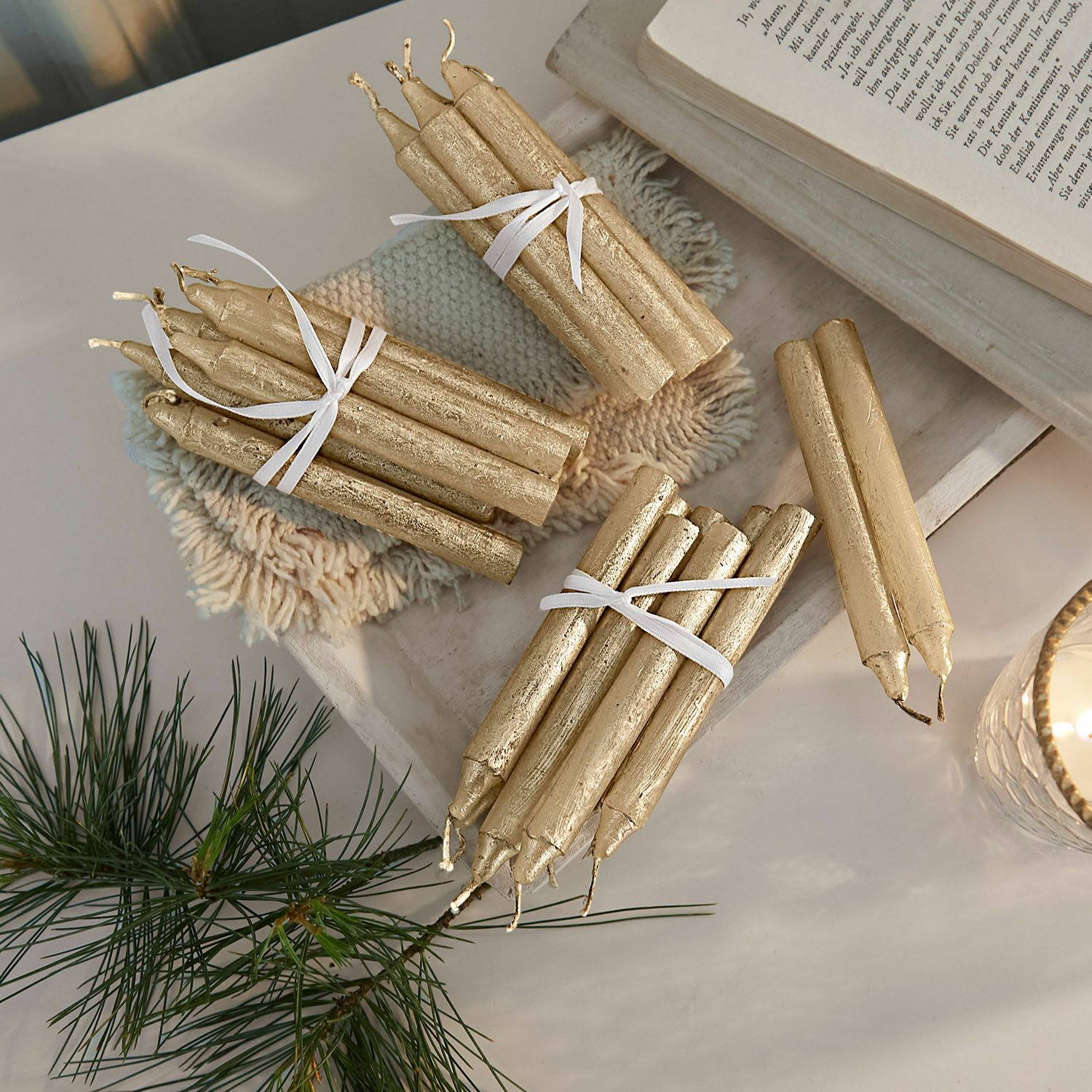 Set goldener Wachskerzen, festliche Tischdekoration mit natürlichem Kiefernzweig