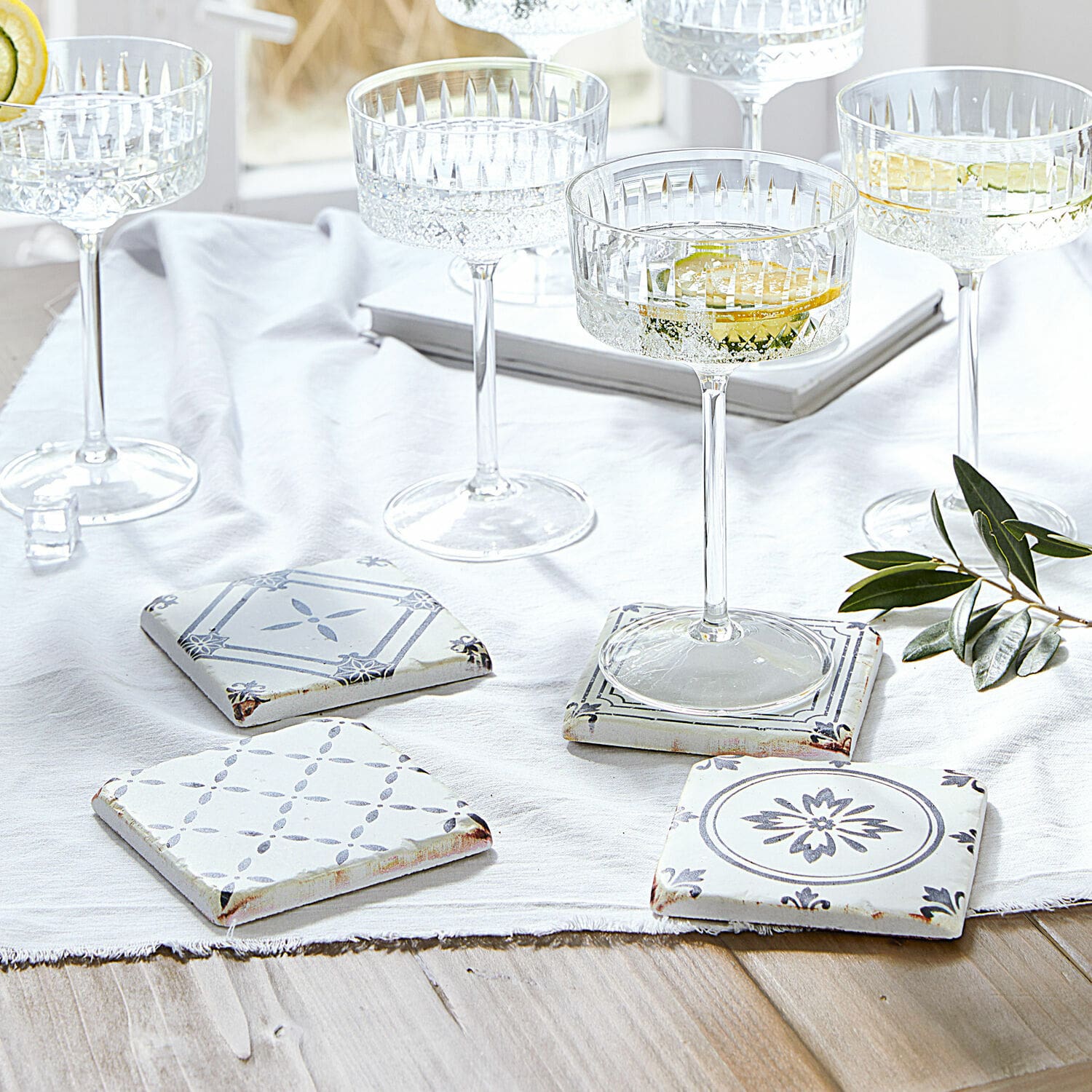 Untersetzer 4er Set Emma Set aus weißen und grauen Keramik-Untersetzern mit Muster auf hellem Holztisch mit Gläsern