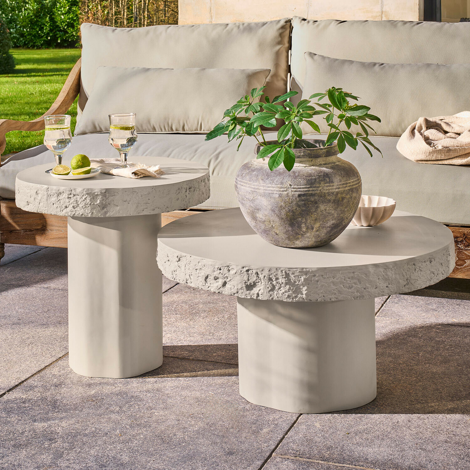 Couchtisch 2er Set Tivoliq Set aus zwei runden Beistelltischen aus hellgrauem Beton auf Terrasse mit Pflanze und Getränken