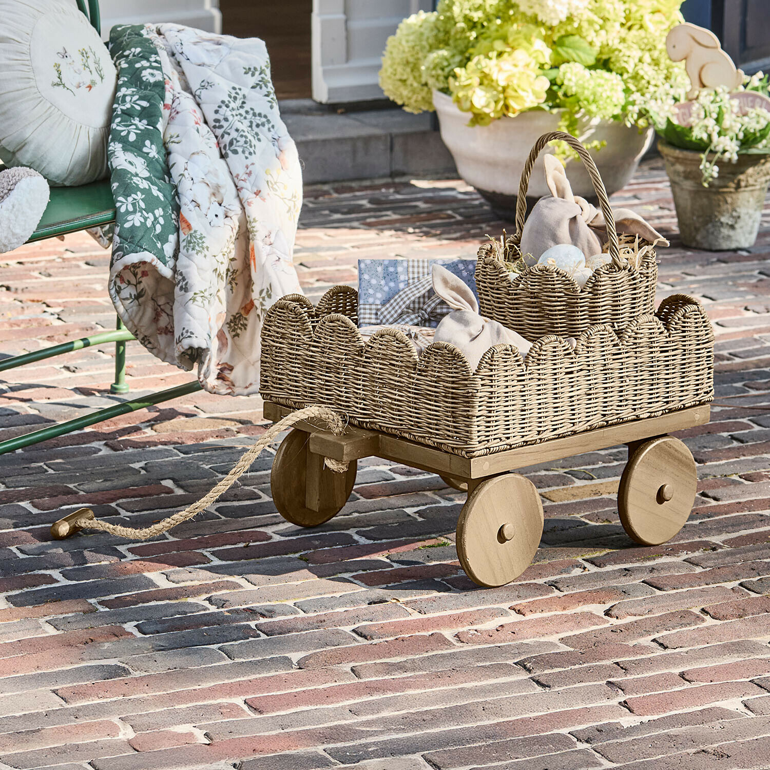 Kinderbollerwagen Whimsywood Holzwagen mit naturfarbenem Korb aus Weide auf Terrasse mit Osterdekorationen