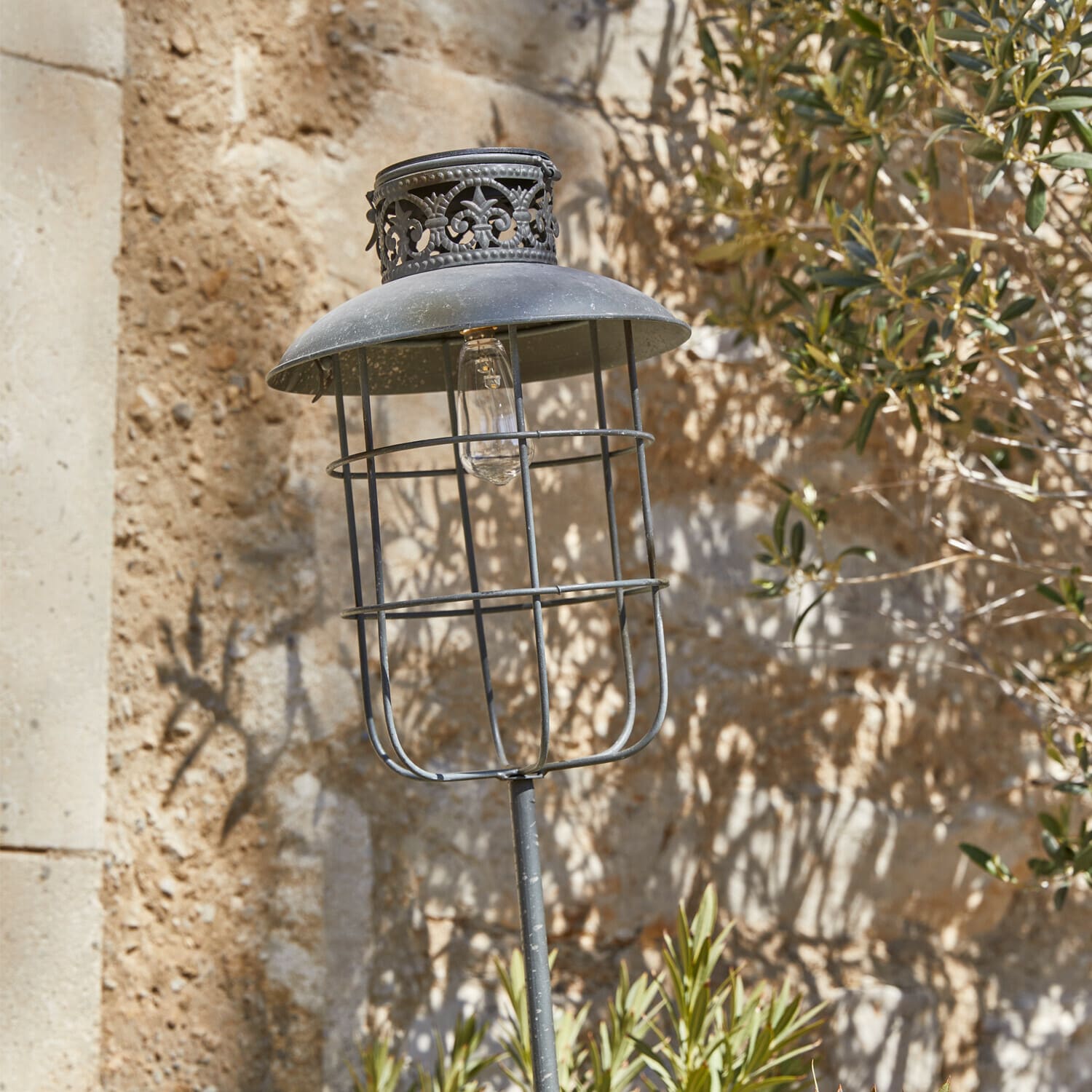 Metall-Gartenlampe im Vintage-Stil mit schwarzem Schirm und dekorativem Muster vor Steinmauer