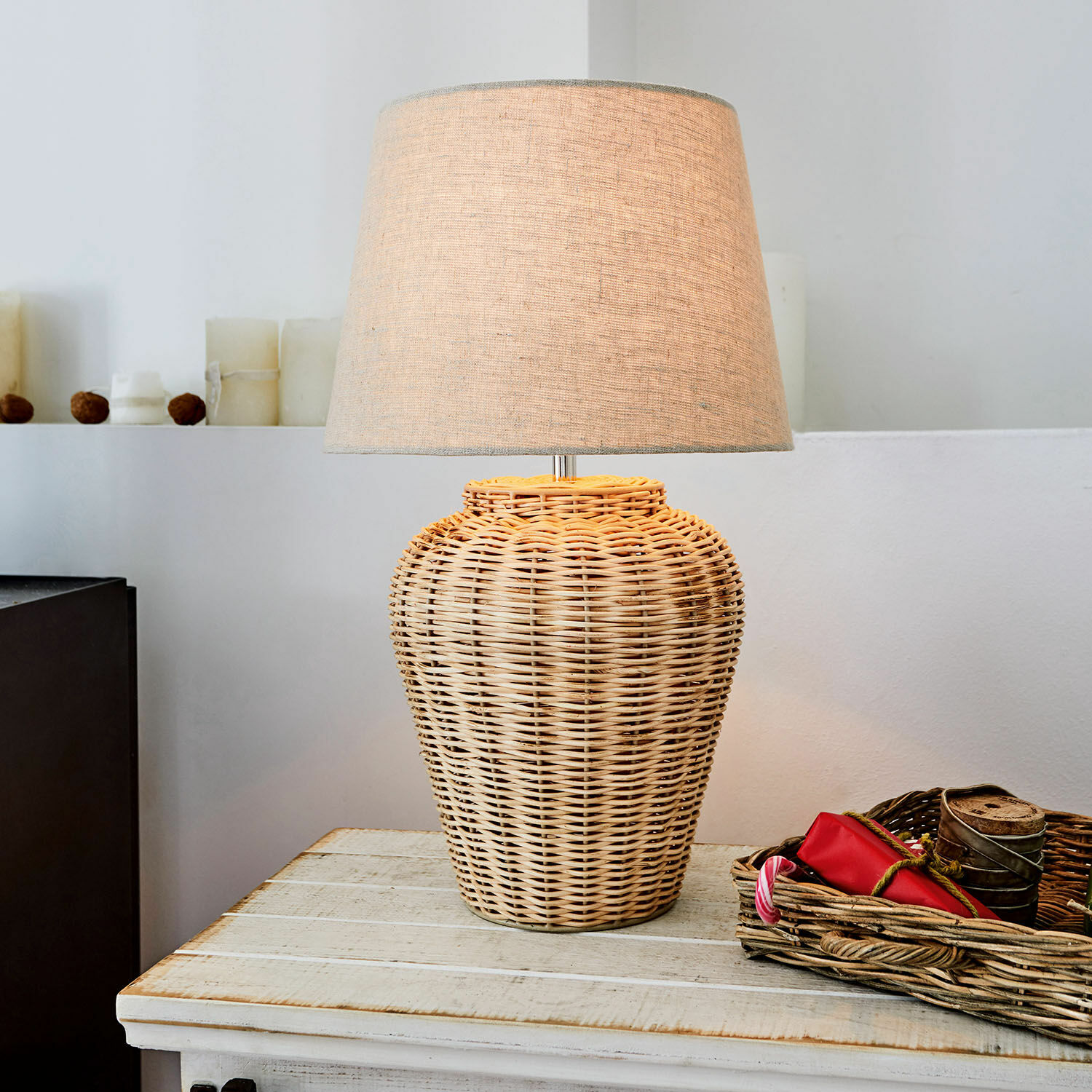 Tischlampe aus geflochtener Weide mit beigem Lampenschirm auf Holztisch, Wohnaccessoire