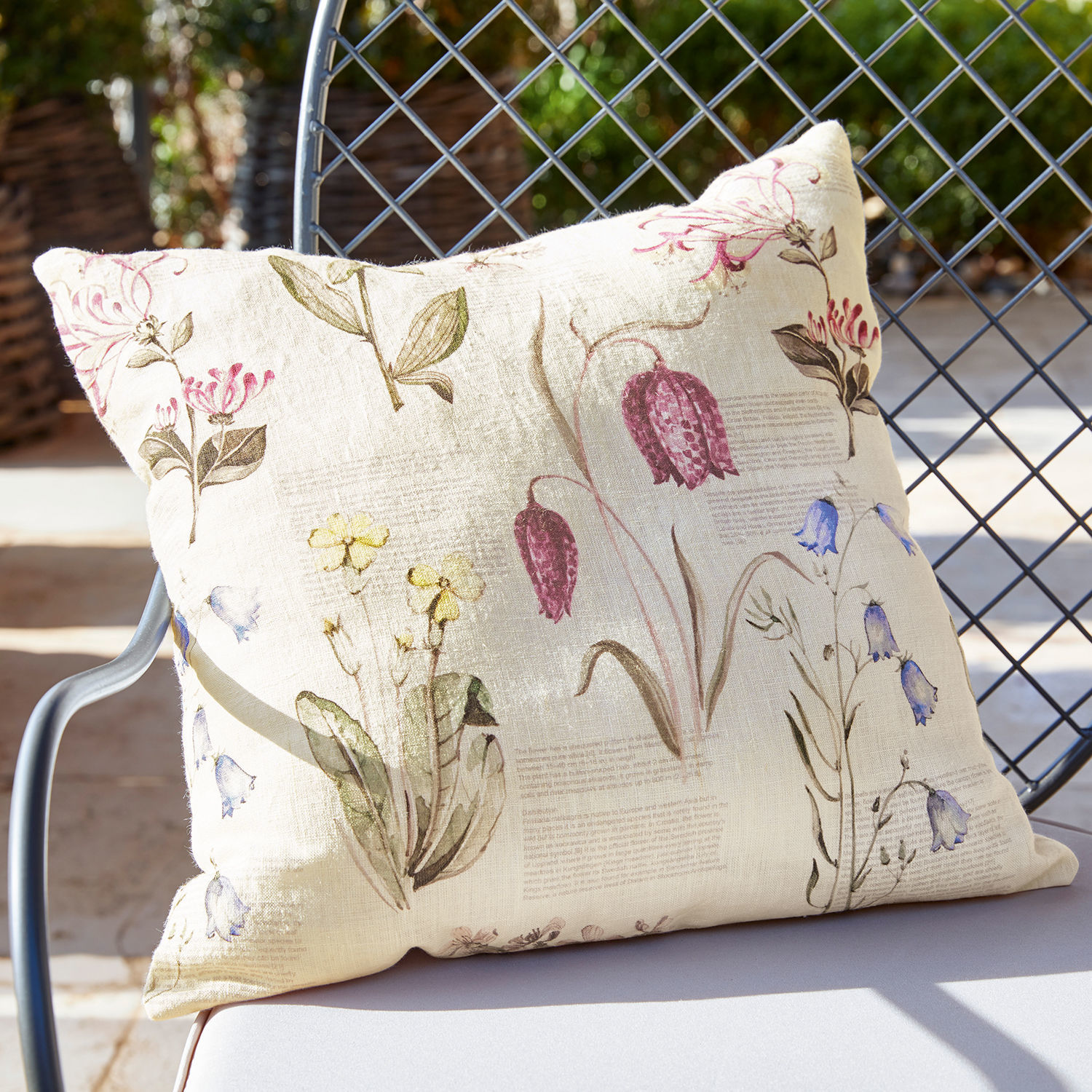Kissenhülle Fournier Beige Leinenkissen mit vintage Blumenmuster auf Gartenstuhl im Sonnenlicht