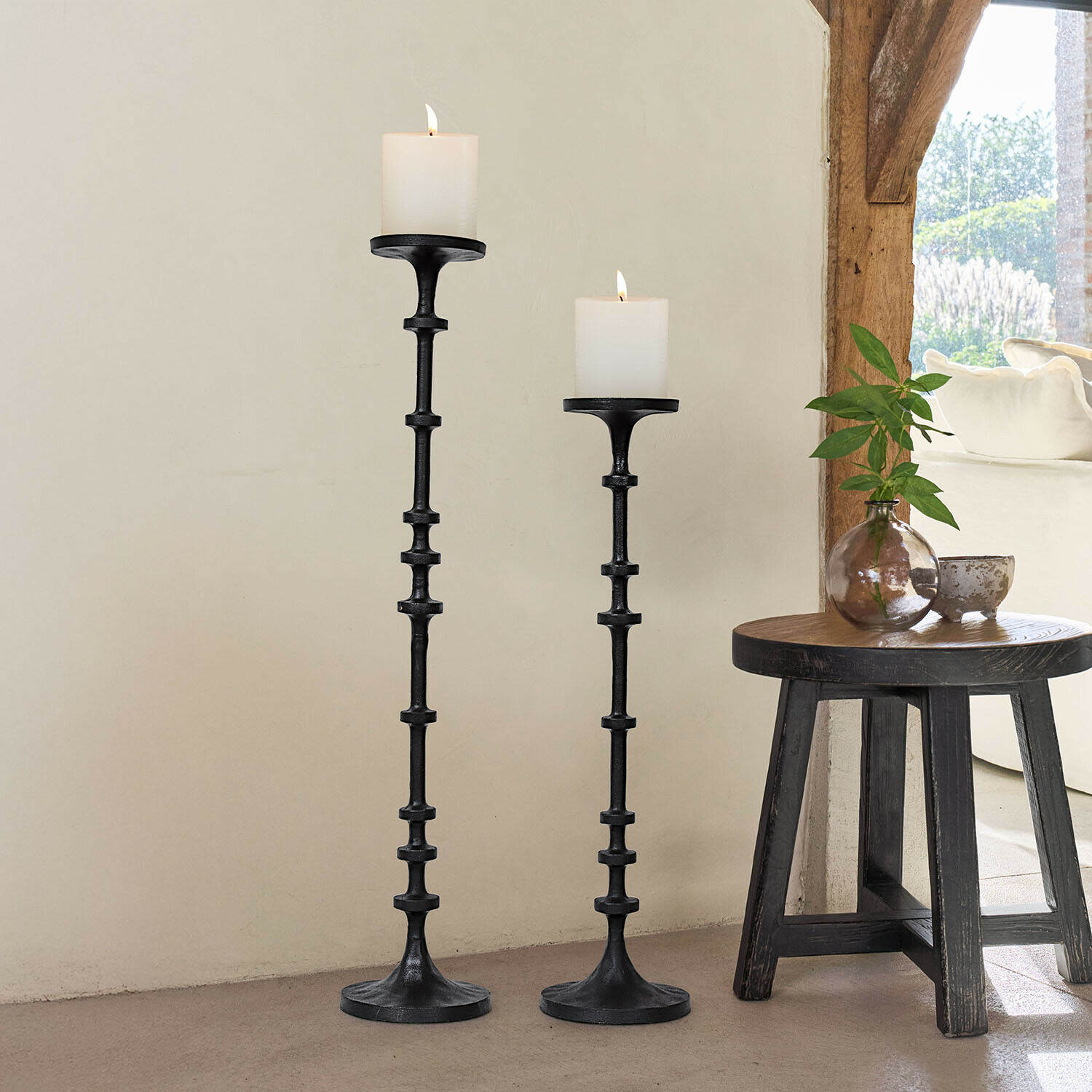 Set aus zwei schwarzen Metall-Kerzenhaltern mit weißen Kerzen, natürliche Wohnraumdekoration mit Licht