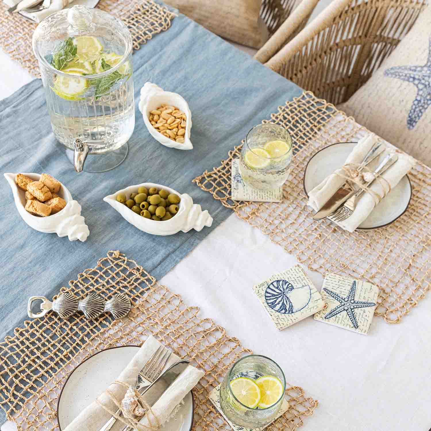 Sommerlicher Tisch mit maritimer Dekoration, weißen Muschel-Schalen aus Keramik mit Snacks und Limonade