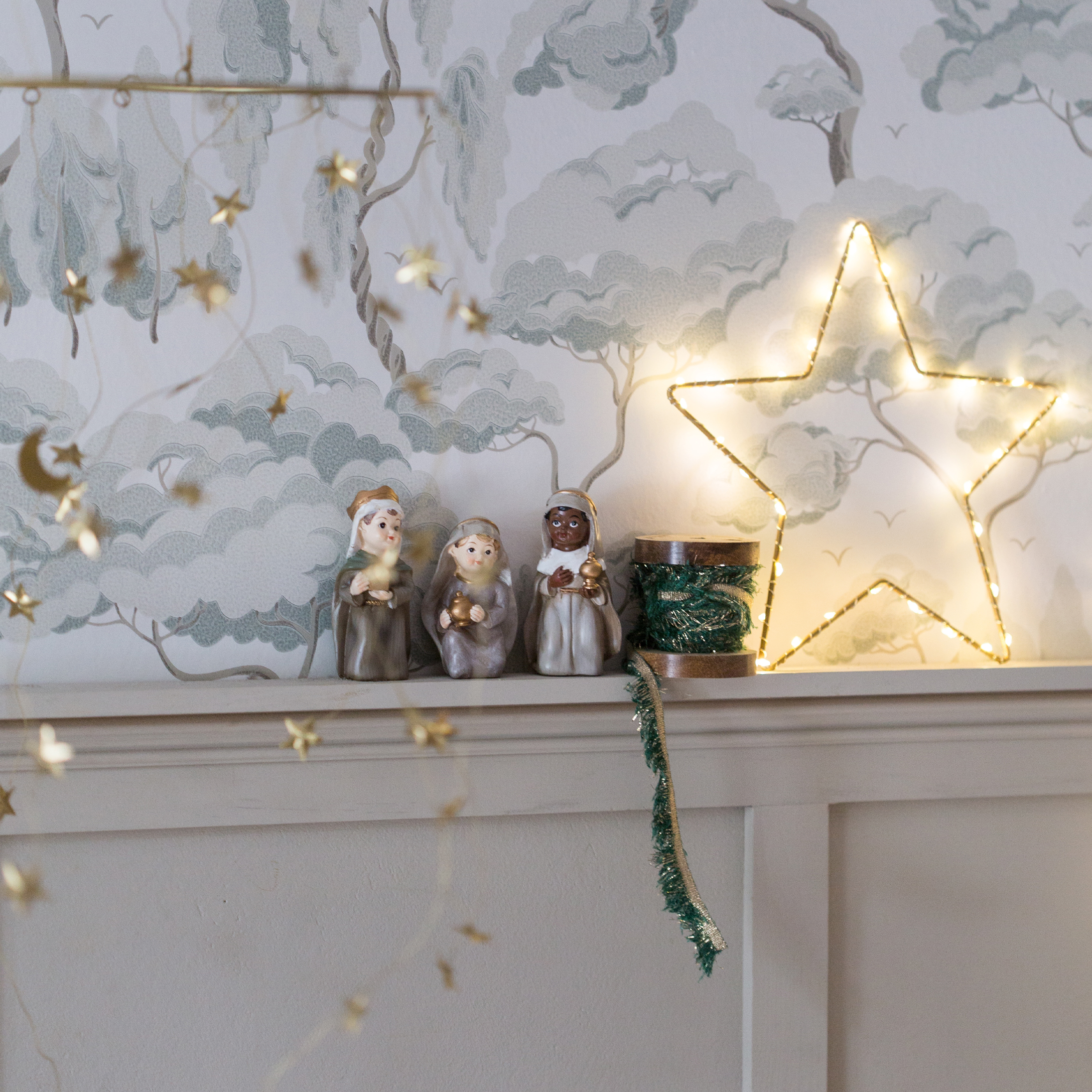 Weihnachtsdekoration mit drei Heiligen Drei Könige Figuren und beleuchtetem Stern auf weißem Regal