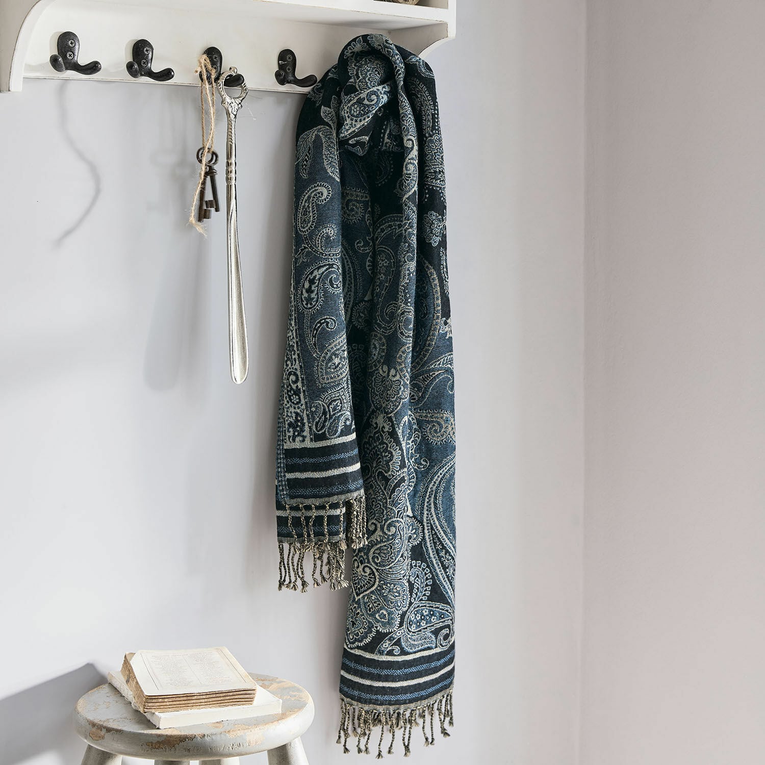 Schal Eloas Dunkelblauer Schal mit Paisley-Muster und Fransen an weißem Haken in hellem Raum