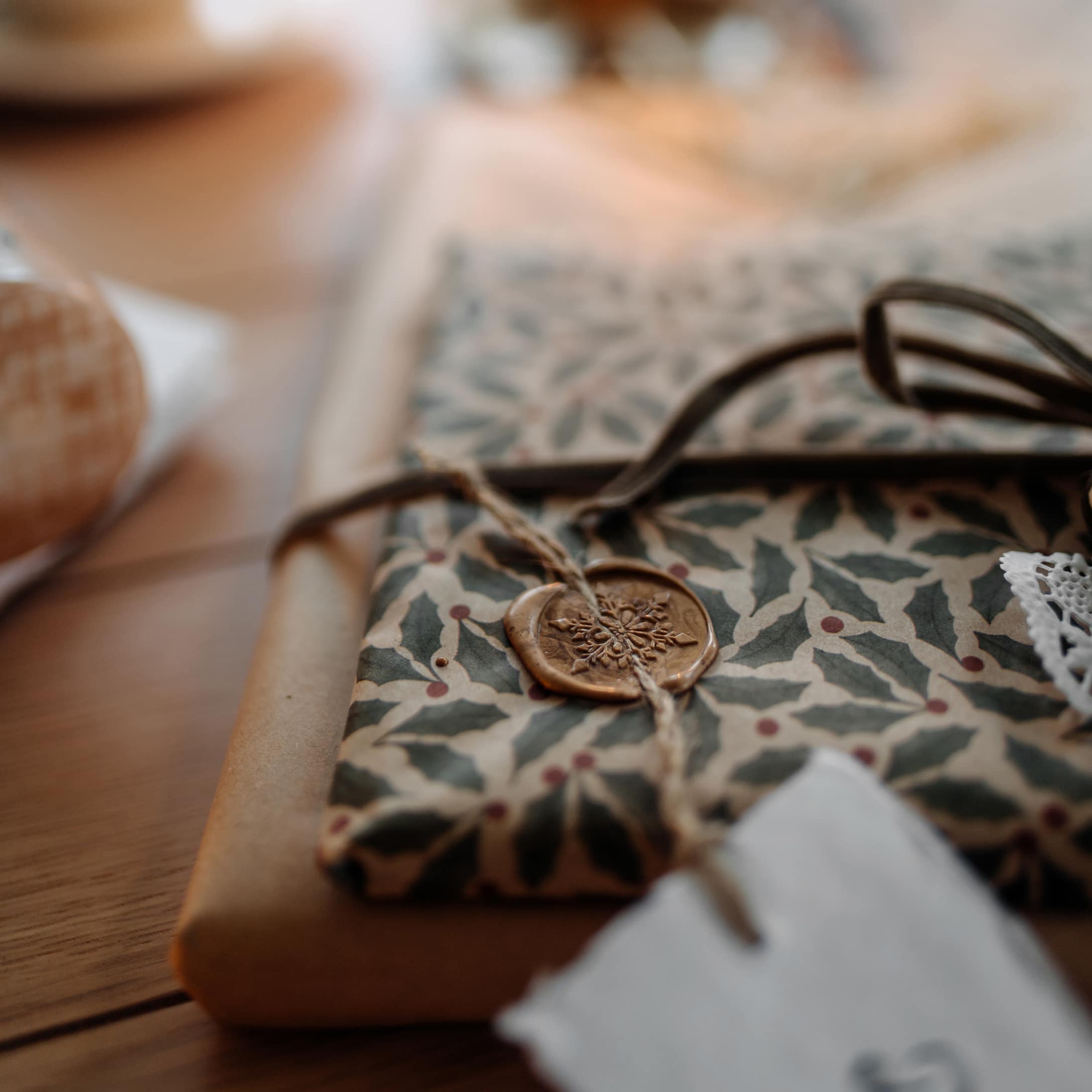 Elegante Geschenkverpackung mit Stechpalmenmuster und dekorativem Wachssiegel