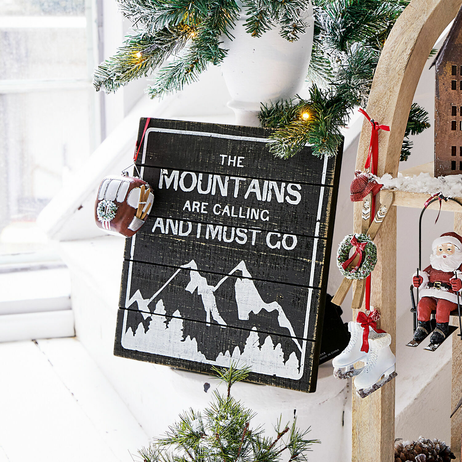 Dekoboard Mountain Holz-Wanddekoration mit Bergmotiv und Schriftzug, geschmückt mit Tannenzweigen und Weihnachtsanhängern