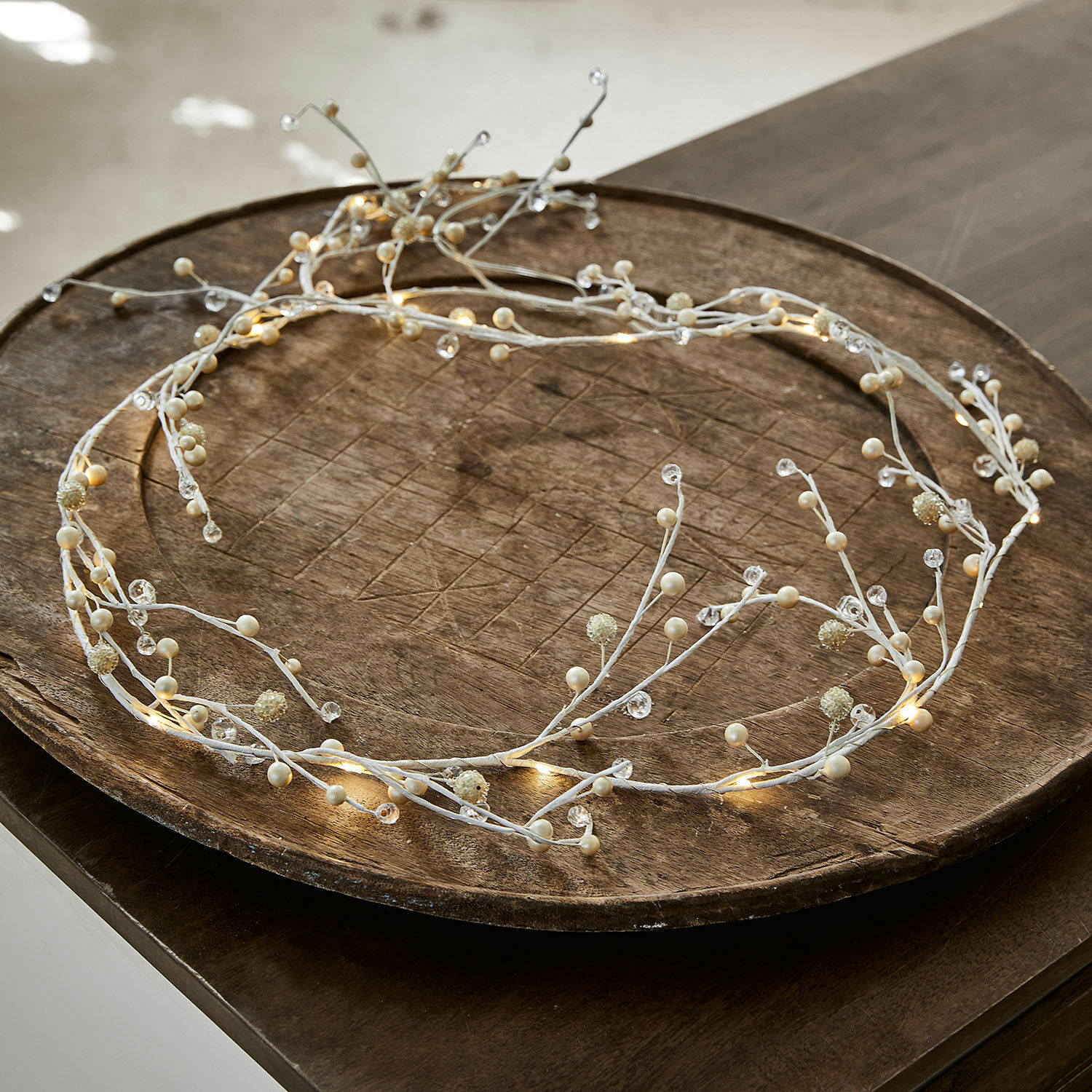 Zarter weißer LED-Dekokranz mit Perlen auf Holztablett, festliche Beleuchtung für Zuhause