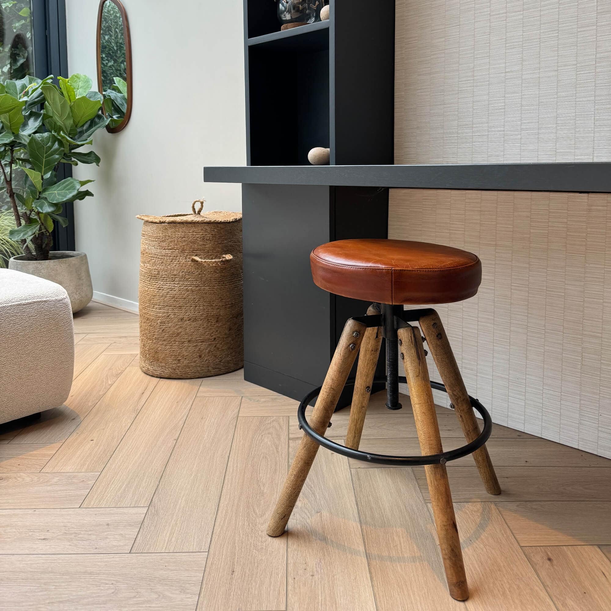 Barhocker mit braunem Lederpolster und Holzbeinen auf hellem Holzboden