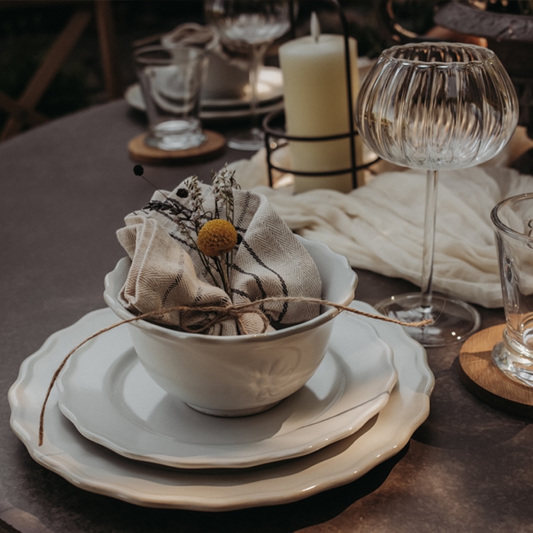 Set aus weißer Keramik mit Schüssel, Tellern und Leinenserviette mit Blumendekor auf Tisch