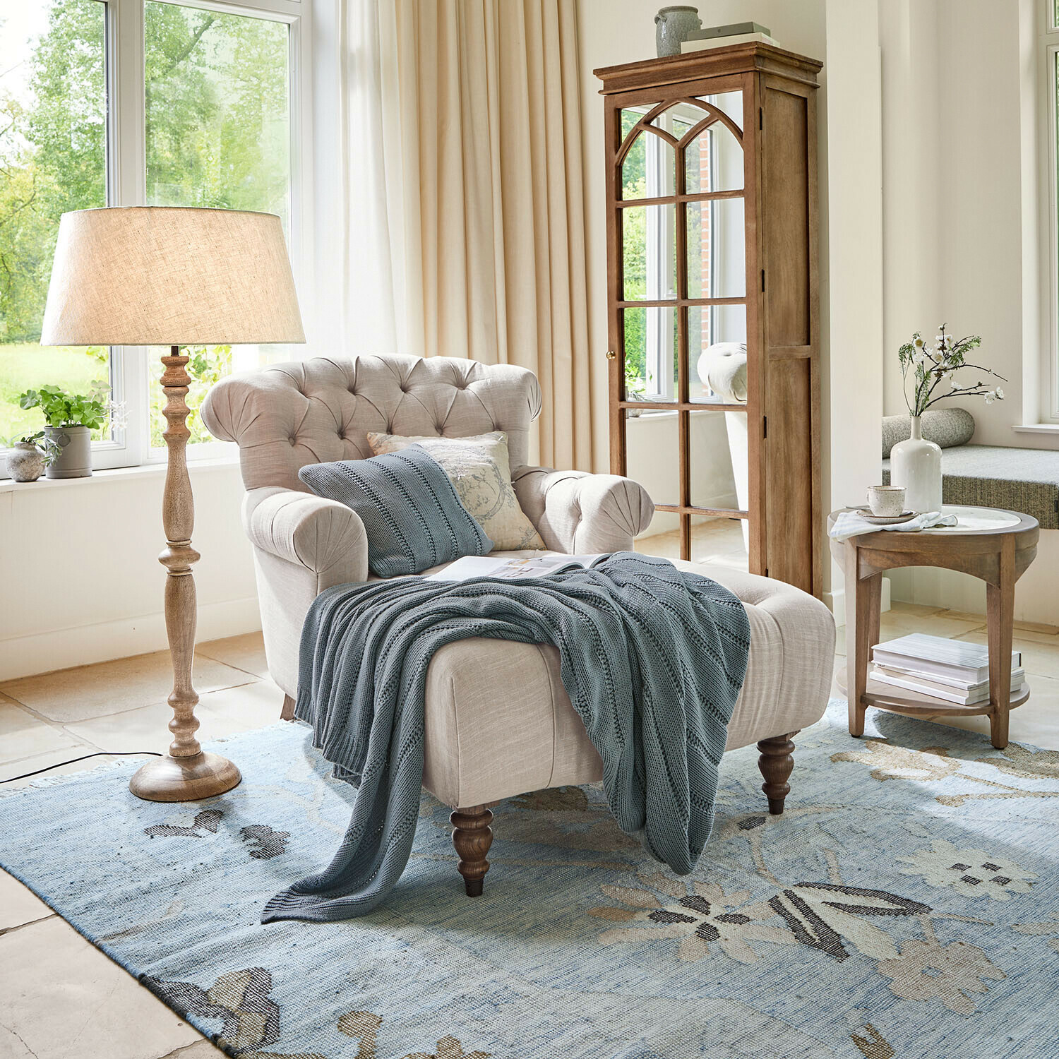 Chaiselongue Springfield Village Beiger Polsterfessel mit gesteppter Rückenlehne und blauem Strickplaid auf blauem Teppich im hellen Wohnzimmer