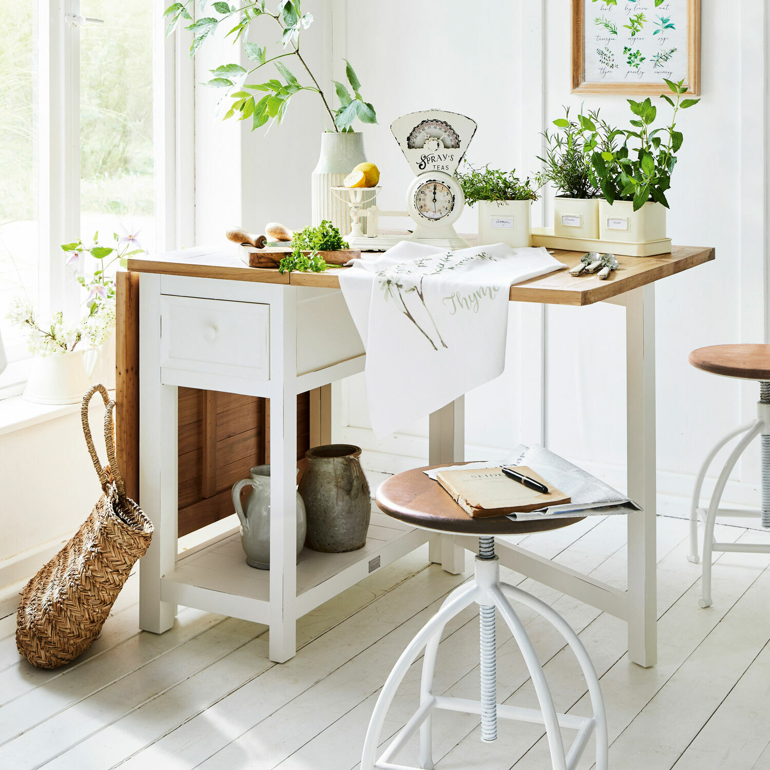 Weißer Holztisch mit hellem Holzplatte und grünen Pflanzen in Töpfen in der Küche