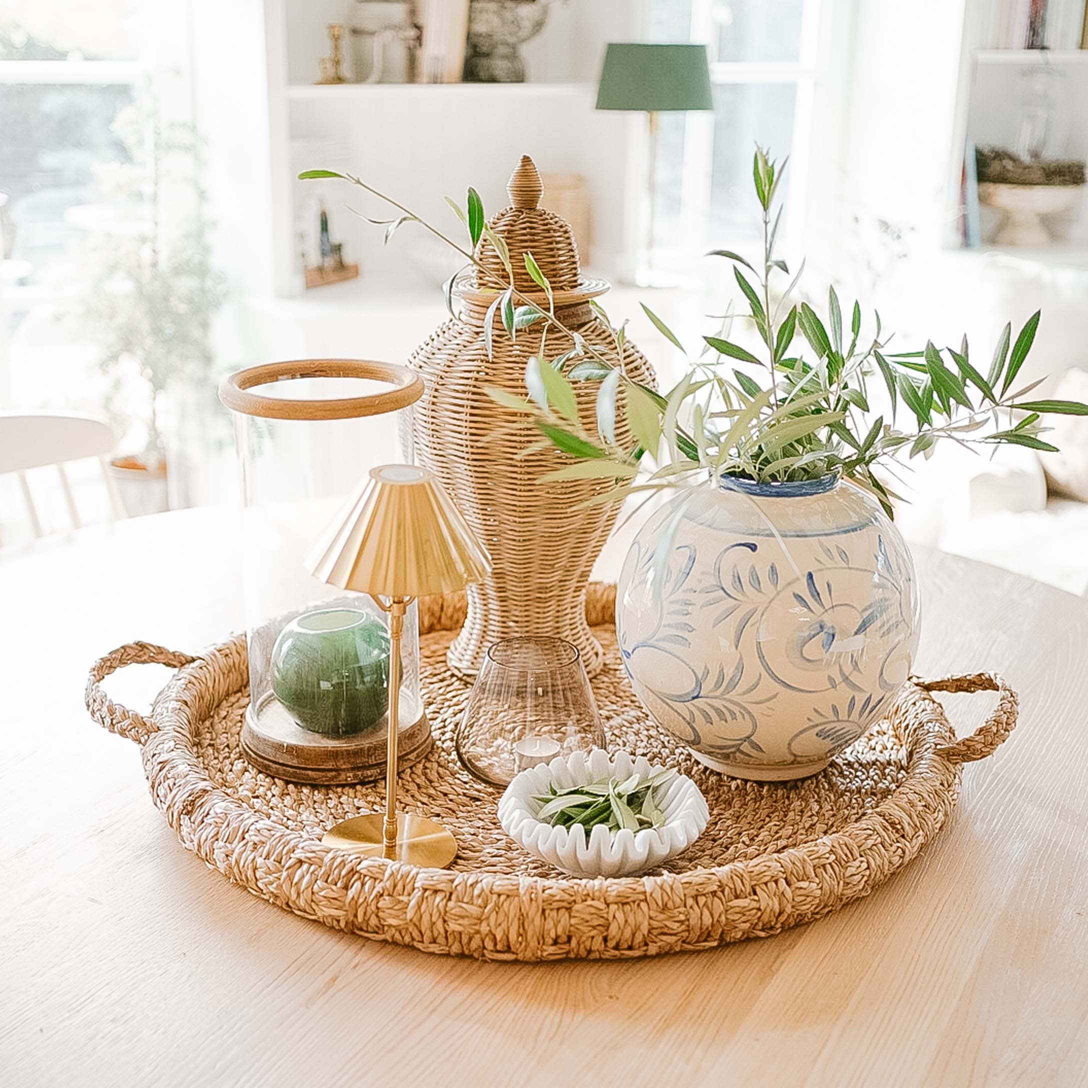 Rattantablett mit Keramikvase und grünen Zweigen als natürliche Wohnraumdekoration