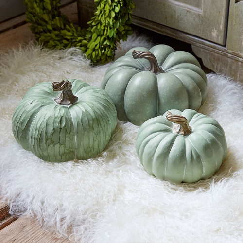 Drei dekorative grüne Kürbisse auf weißem Fellteppich, herbstliche Wohnaccessoires