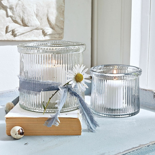Glaswindlichter aus geriffeltem Glas mit weißen Kerzen und dekorativem Band mit Blume.