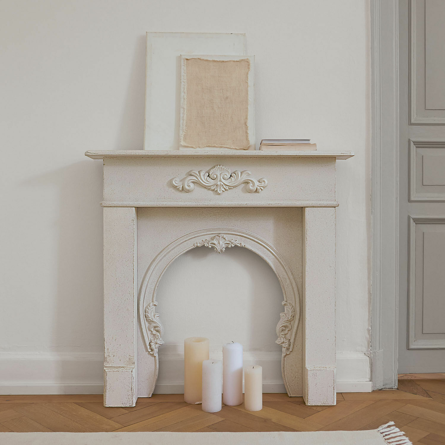 Weißer dekorativer Kaminumrahmung mit Ornamenten und Kerzen auf Holzparkett im Vintage-Stil