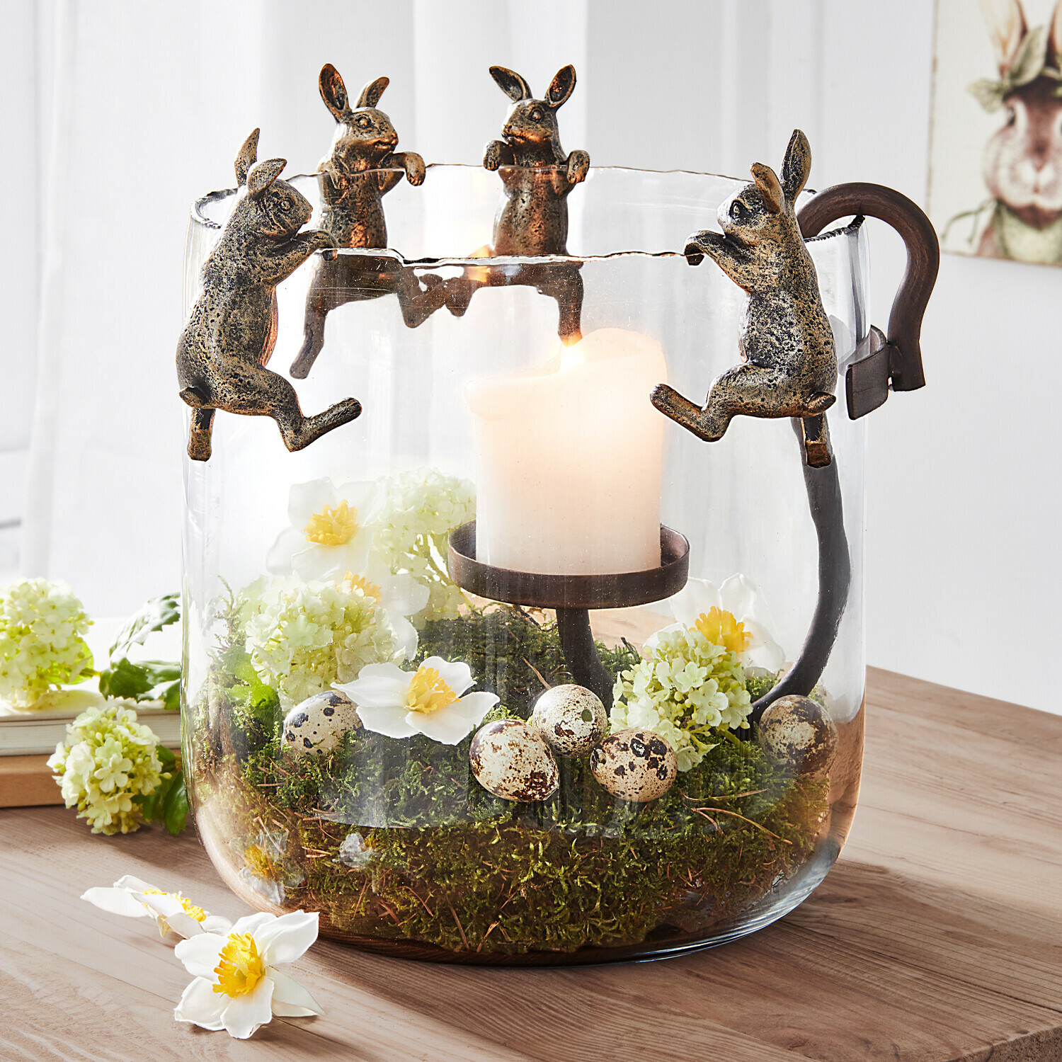 Glaswindlicht mit Metallhasen, weißer Kerze und Moos- sowie Eierschmuck, frühlingshafte Dekoration