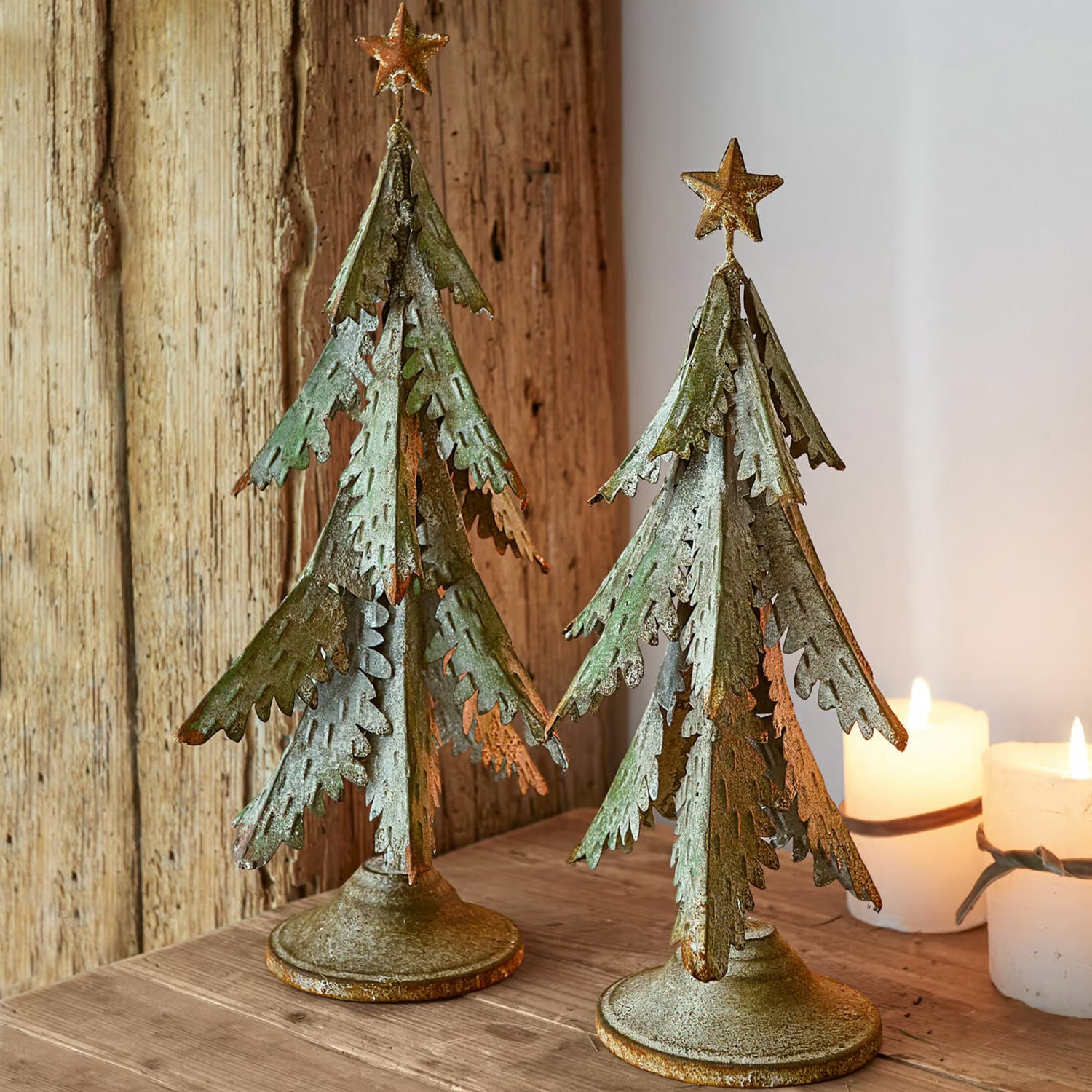 Zwei grüne Metall-Weihnachtsbäume mit goldenen Sternen als Tischdekoration im rustikalen Stil