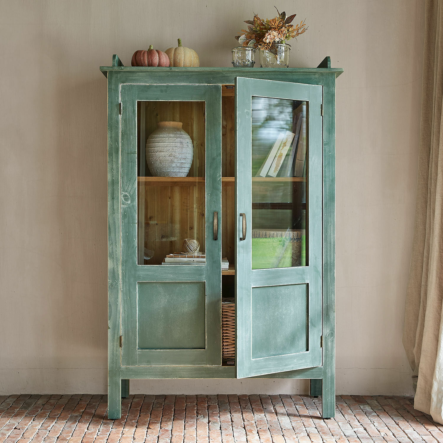 Grüner Holzschrank mit Glastüren und Dekorationen oben, rustikales Wohnzimmermöbel