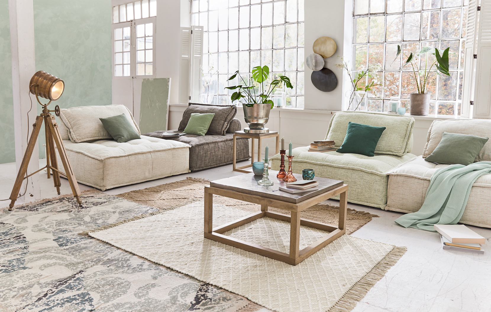 Gemütliches Wohnzimmer mit beigen und grauen Sofas, Holztisch und Loft-Stativlampe