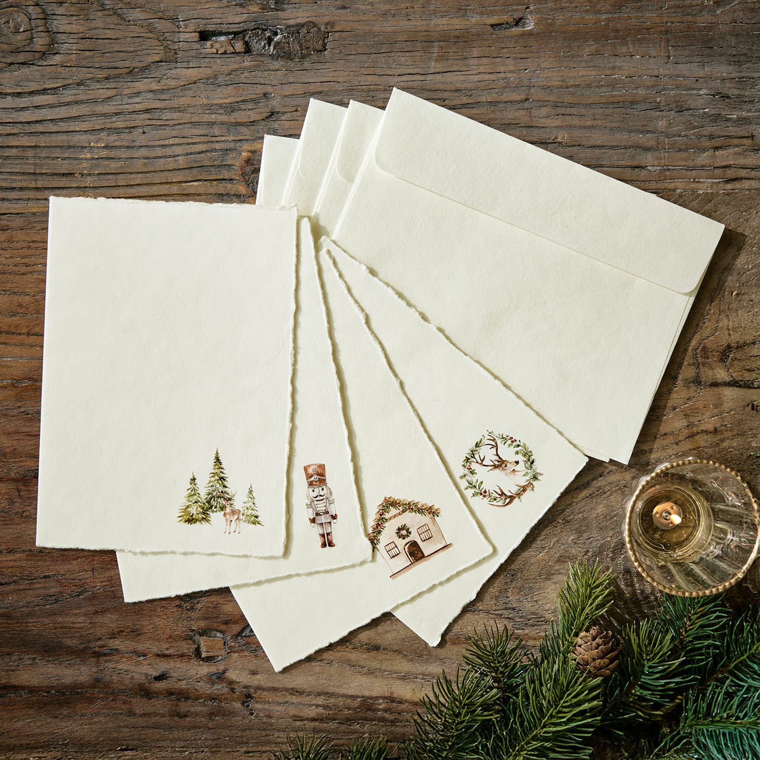Grußkarte 4er Set Lorandis Set aus cremefarbenen Briefkarten und Umschlägen mit Weihnachtsmotiven auf Holztisch mit Tannenzweigen