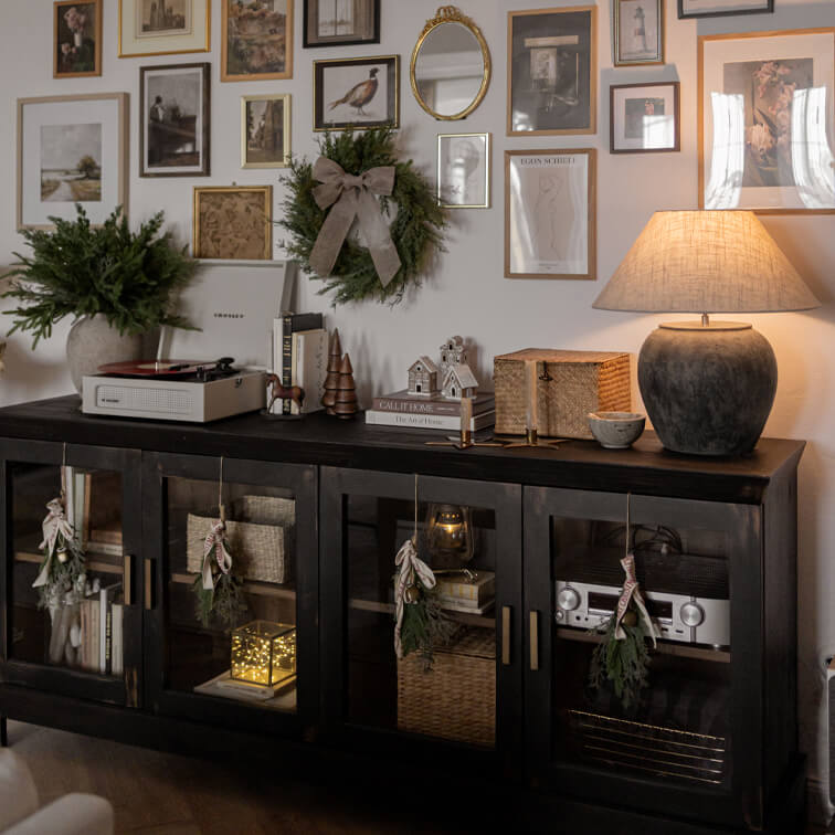 Schwarzer Holzsideboard mit Glastüren, weihnachtlicher Dekoration und Keramiklampe im Wohnzimmer