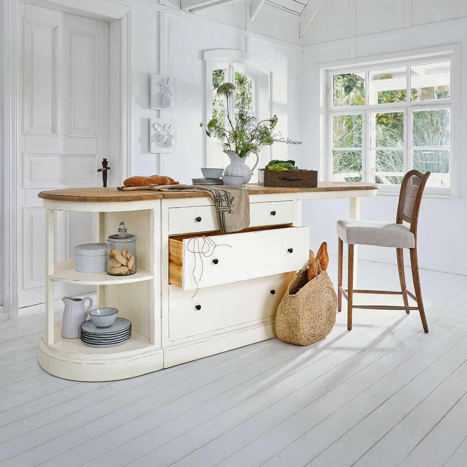 Kremfarbene Kücheninsel mit Holzarbeitsplatte und Schubladen, rustikaler Stil, helles Interieur