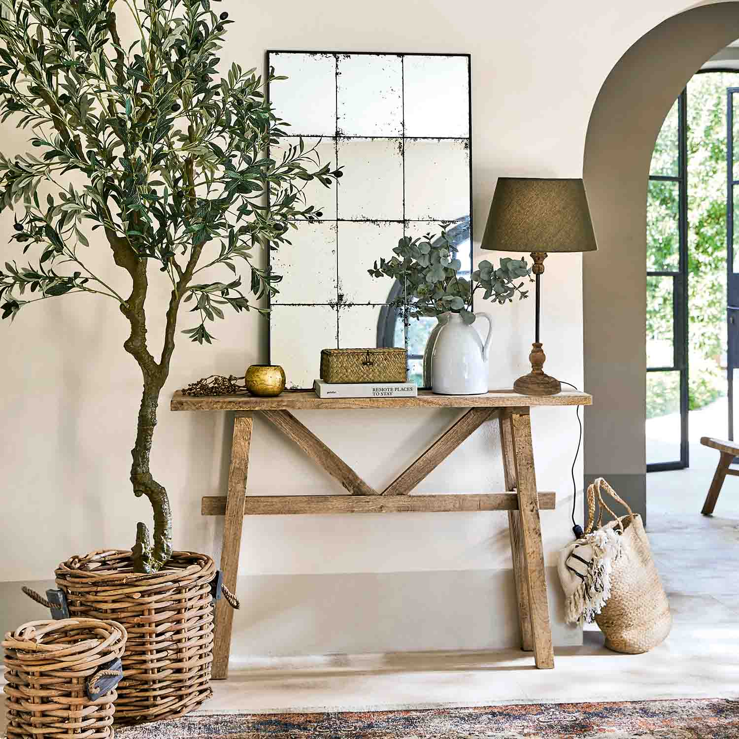 Holzkonsole mit Spiegel, Lampe und Korbdekorationen in hellem, natürlichem Wohnraum