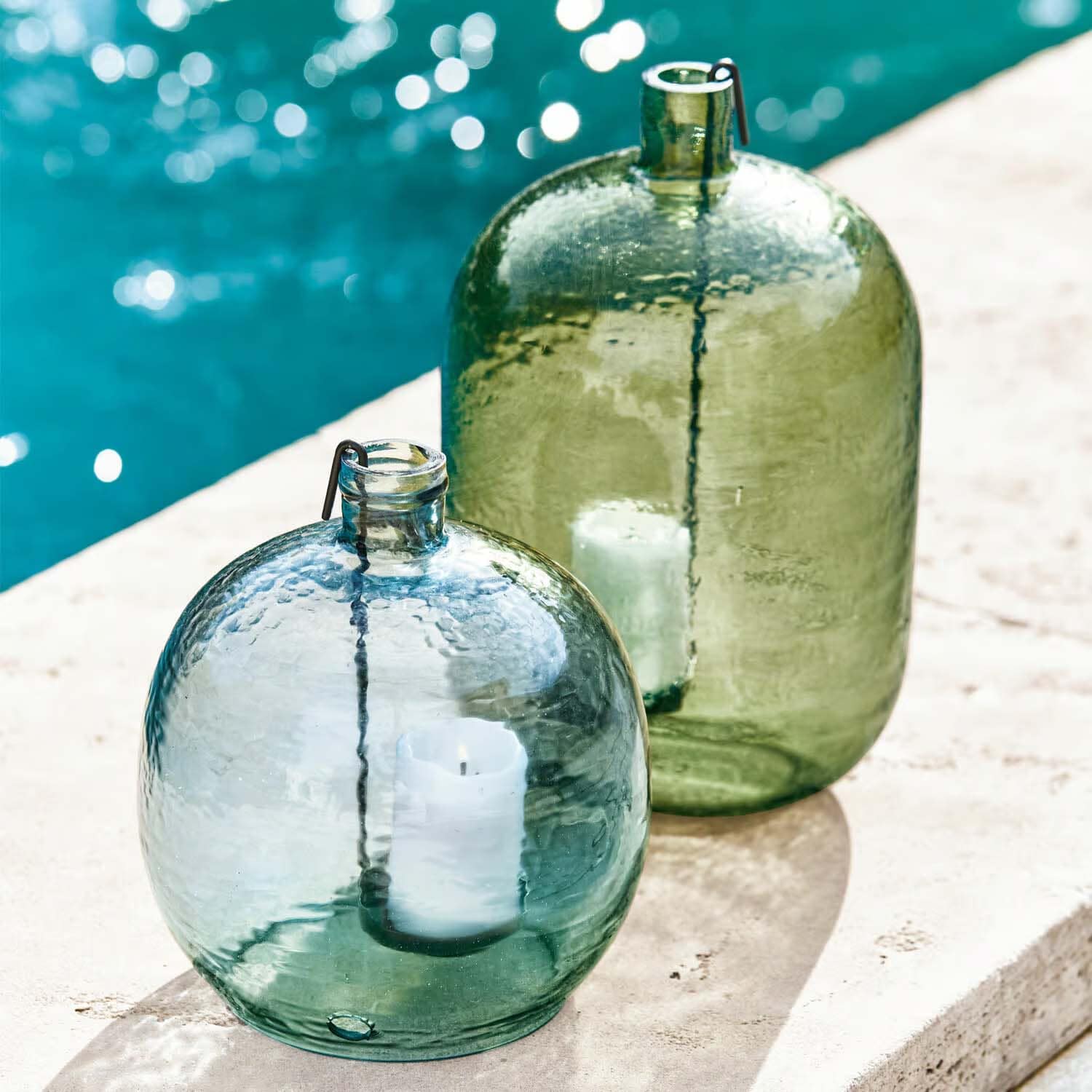 Glaslaternen in Grün und Blau mit weißen Kerzen, Outdoor-Dekoration am Poolrand