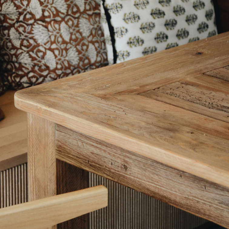 Tisch aus hellem Holz mit rustikalem Design und dekorativen Kissen im Hintergrund, Wohnzimmermöbel