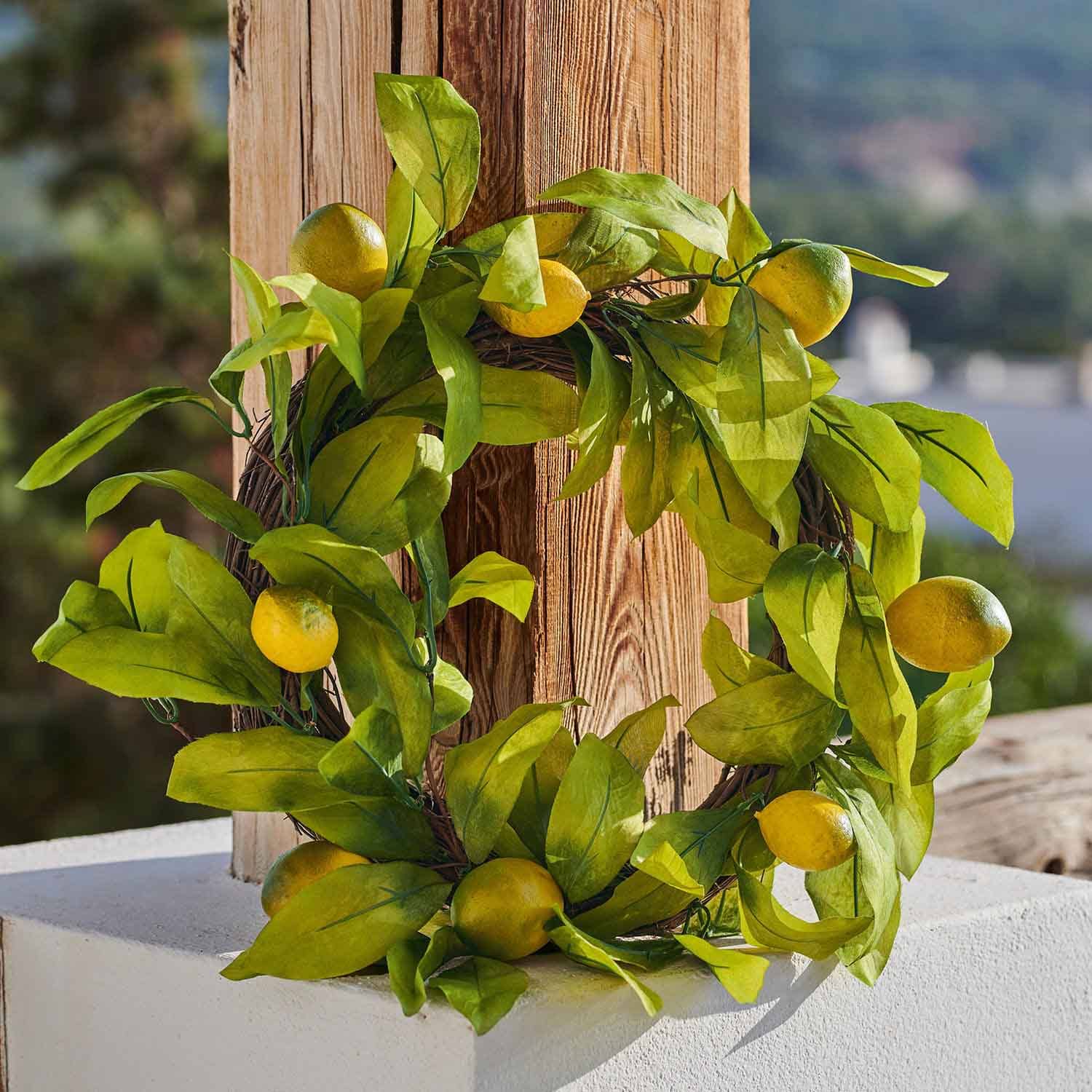 Dekorativer Kranz mit gelben Zitronen und grünen Blättern vor Holz, sommerliche Dekoration