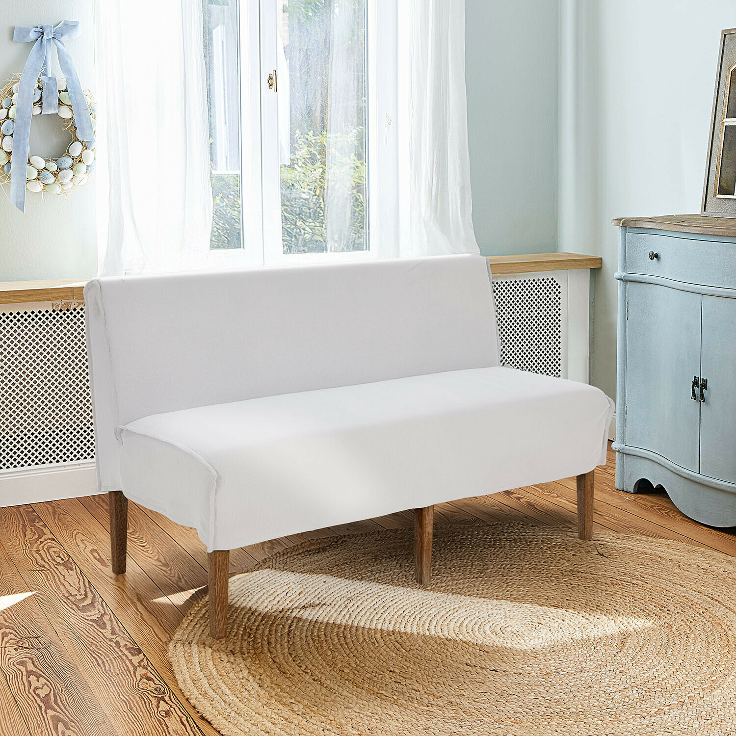 Weißes Sofa mit Holzbeinen auf rundem Jute-Teppich in hellem, gemütlichem Raum