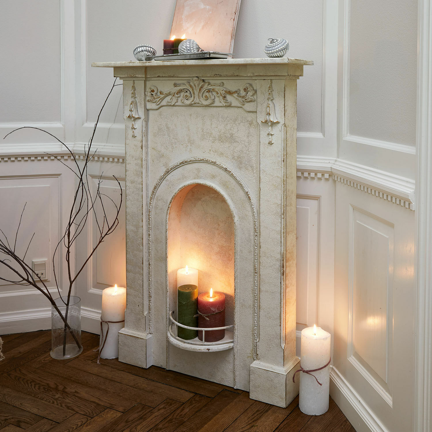 Kaminkonsole Câlanette Dekorativer weißer Kamin mit verzierten Details und brennenden Kerzen in einem Wohnzimmer mit Holzboden