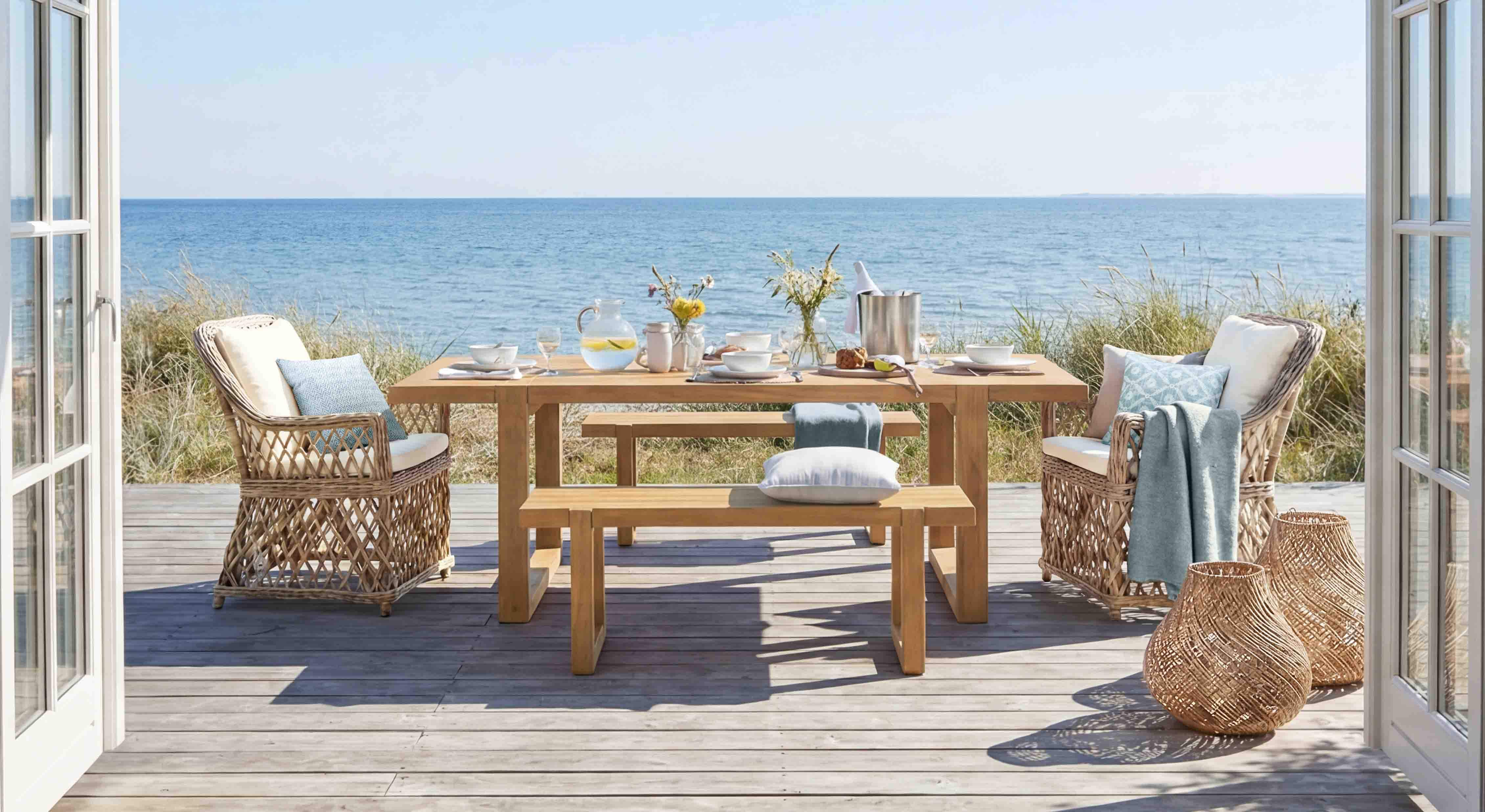 Gartenmöbel-Set aus Holz und Rattan in Naturtönen auf Terrasse mit Meerblick