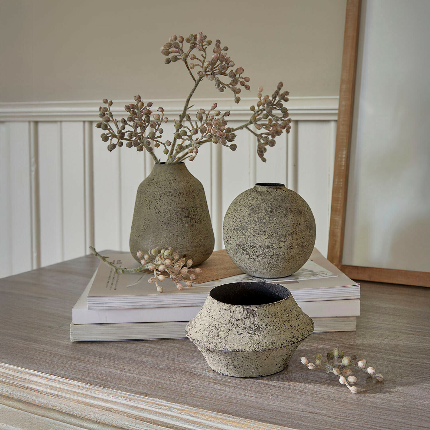 Drei dekorative beige Steingutvasen auf Holztisch mit getrockneten Zweigen als Deko