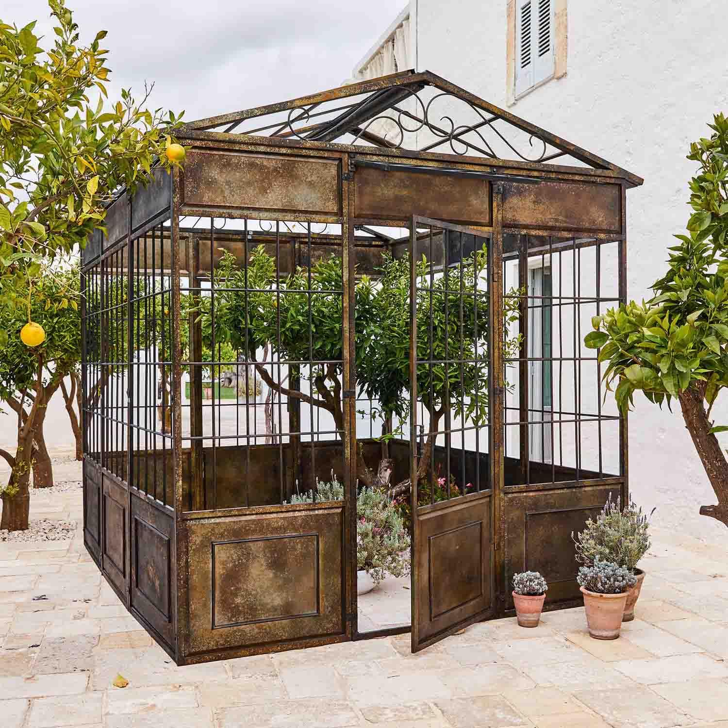 Vintage Metall-Gartenlaube mit Pflanzen und Zitrusbäumen auf steinerner Terrasse